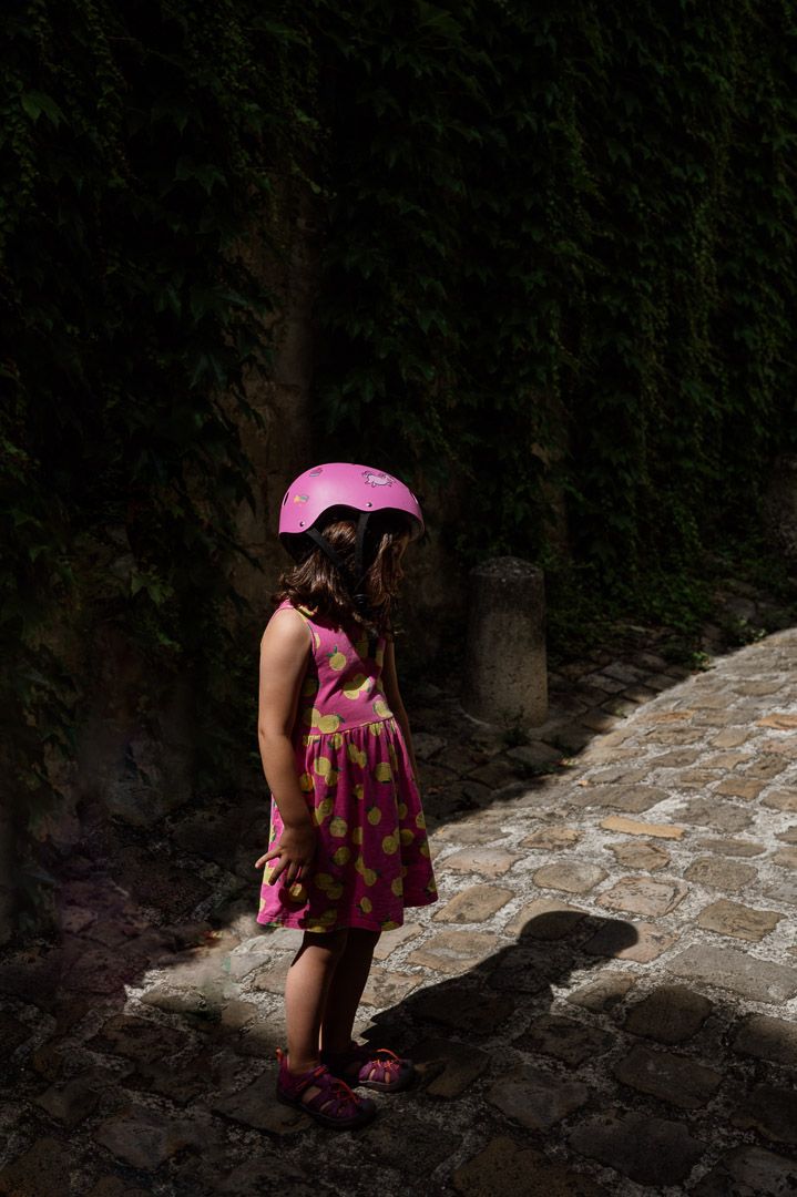 Kind mit pinken Fahrradhelm im Sonnenschein mit dunklen Schatten