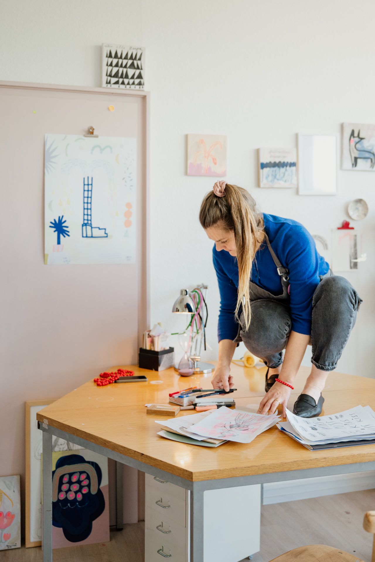 Künstlerin bei der Arbeit im Atelier hockend auf Tisch