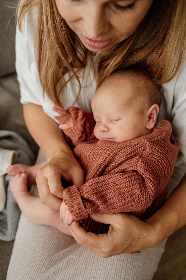 Baby mit dickem Pullover auf Schoß seiner Mama