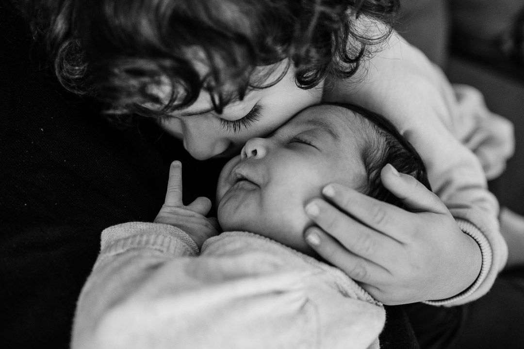 Kleinkind drückt Baby liebevoll an seine Wange