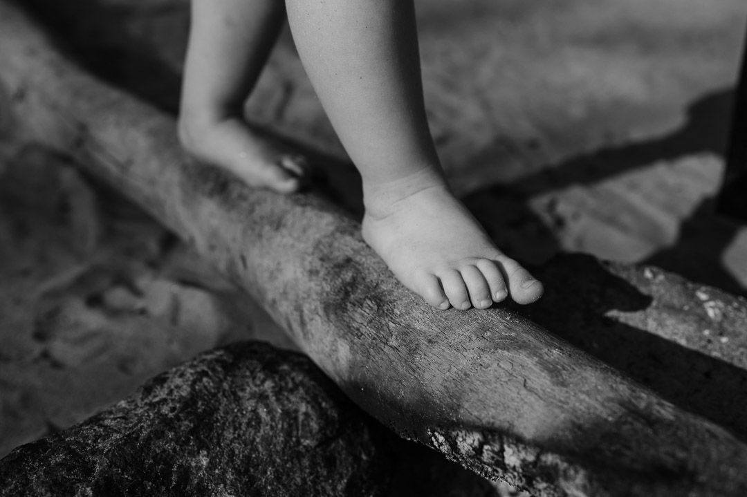 Kinderfüße balancieren auf Treibholz