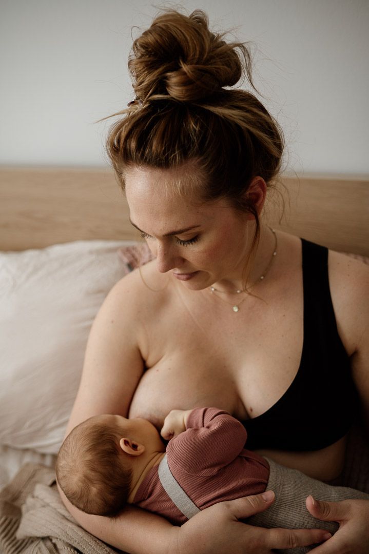 Mutter stillt Baby im Bett bei Homestory