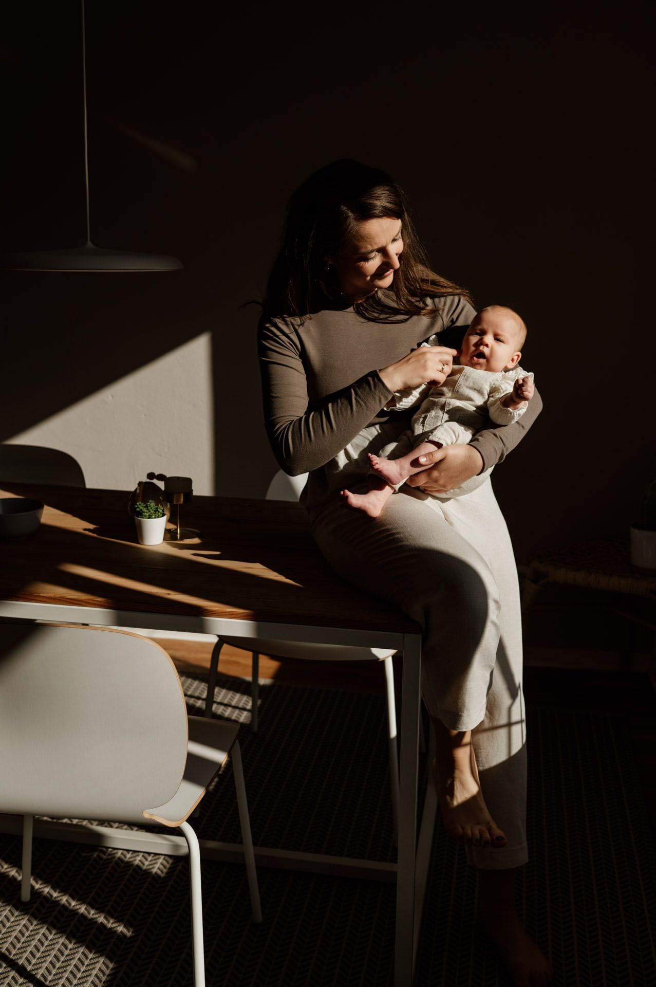 Mama und Baby auf Schoß sitzend auf Tisch im direktem Sonnenschein