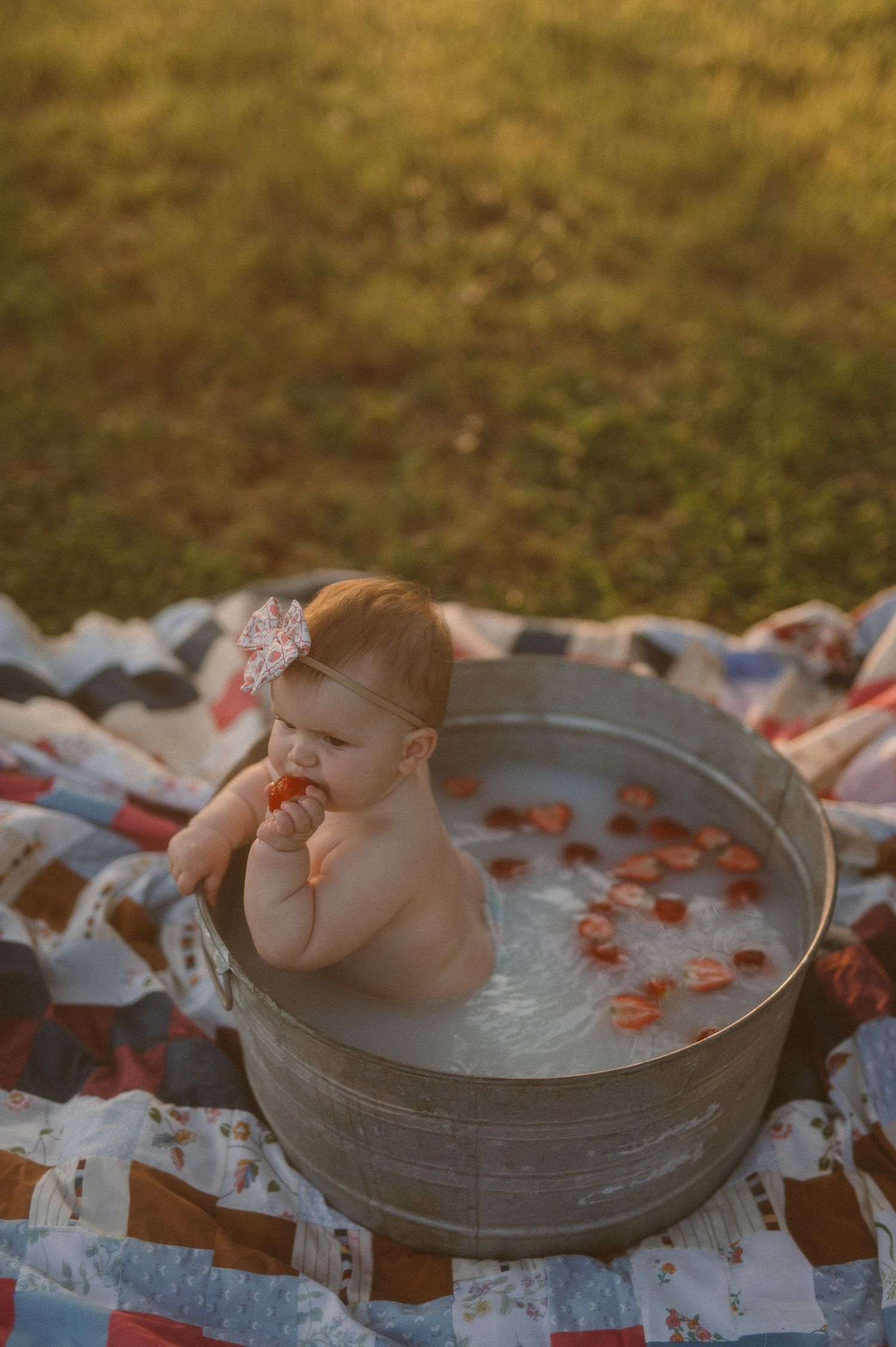 Baby sitting in a metal tub during outdoor milestone session