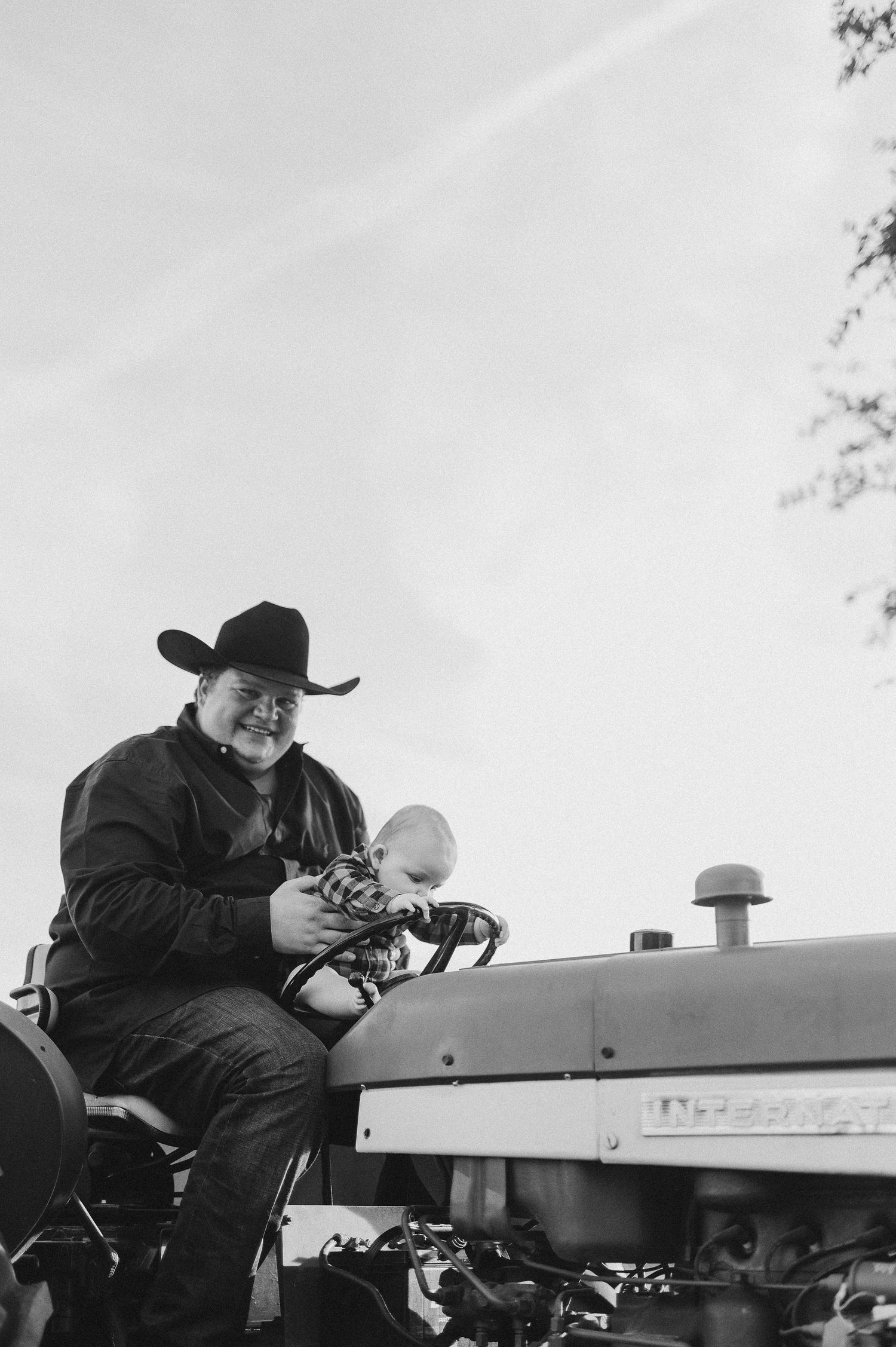 Parent holding baby on a tractor during family session in Azle, Tx