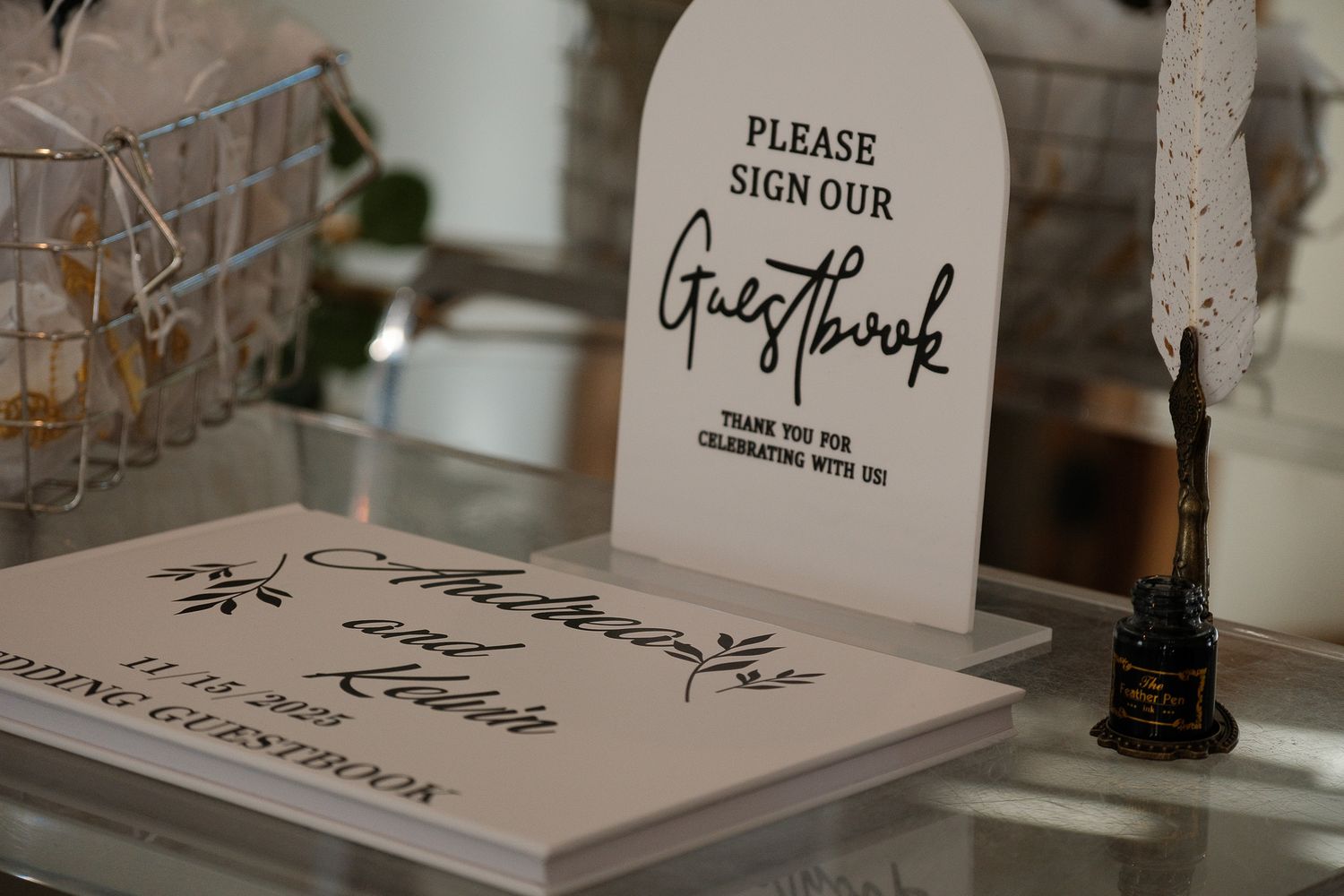 Wedding guestbook display with elegant sign asking guests to sign on a glass table.