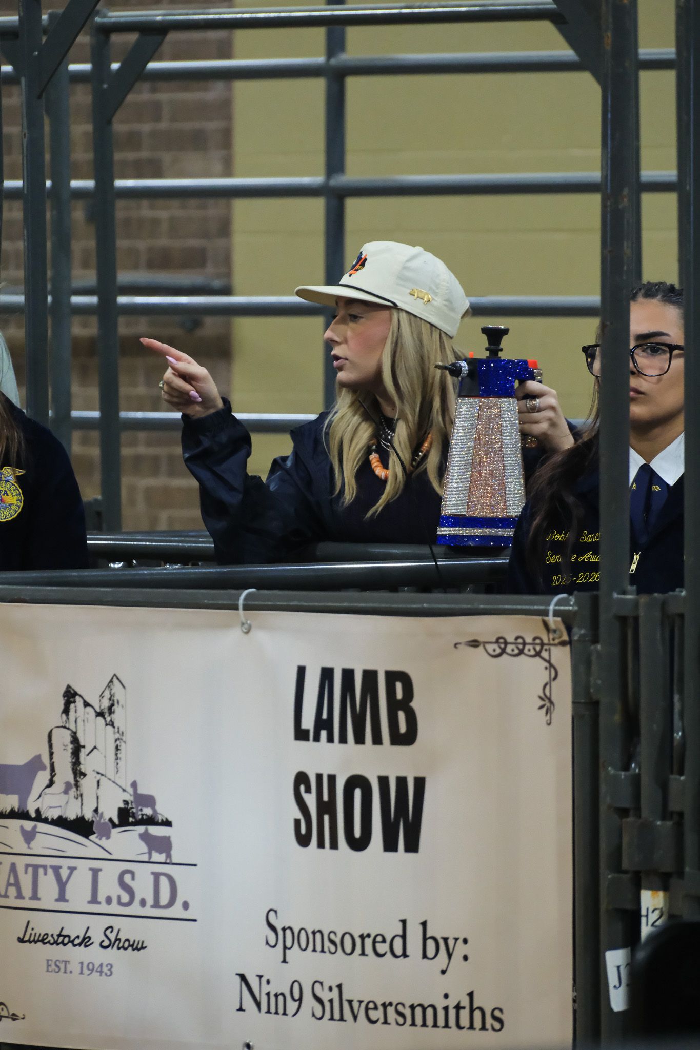 Judge pointing at Katy ISD Lamb Show sponsored by Nin9 Silversmiths livestock event.