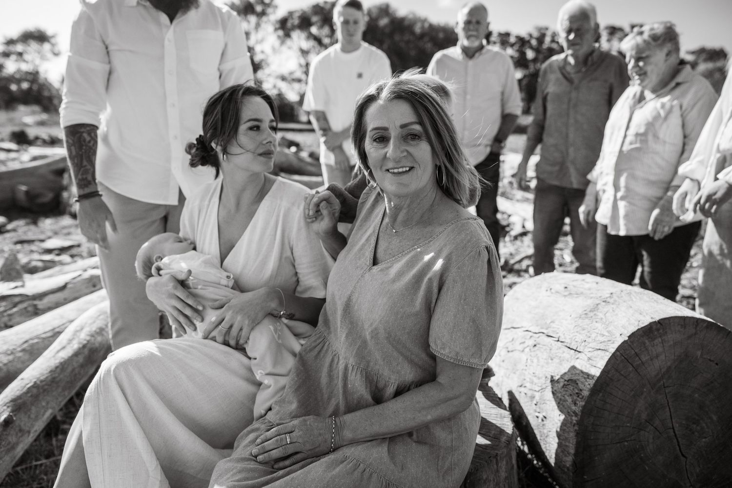 Two women smiling together at an outdoor family gathering in black and white photo.