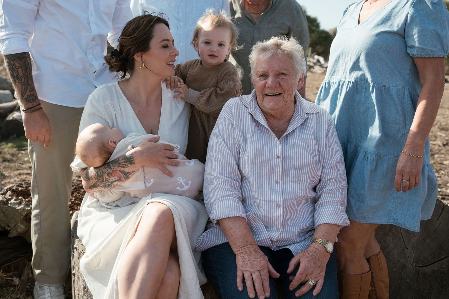 Multi-generational family portrait with grandmother, mother, and young children outdoors.