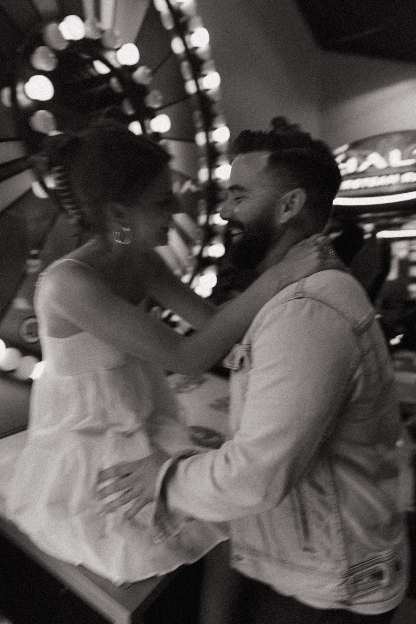 Couple embracing and laughing together in black and white photo at arcade venue.