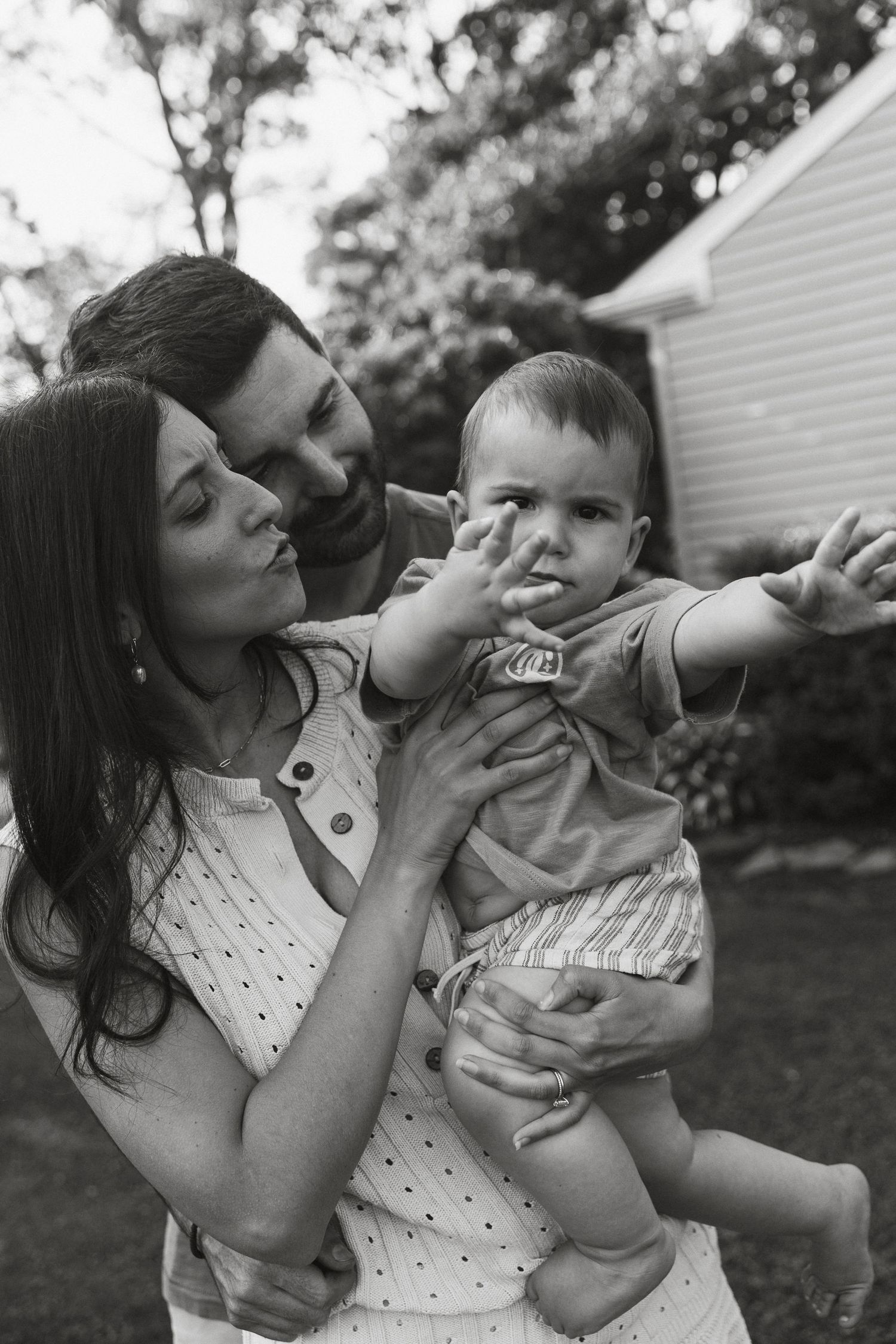 Candid black and white family portrait taken in backyard setting.