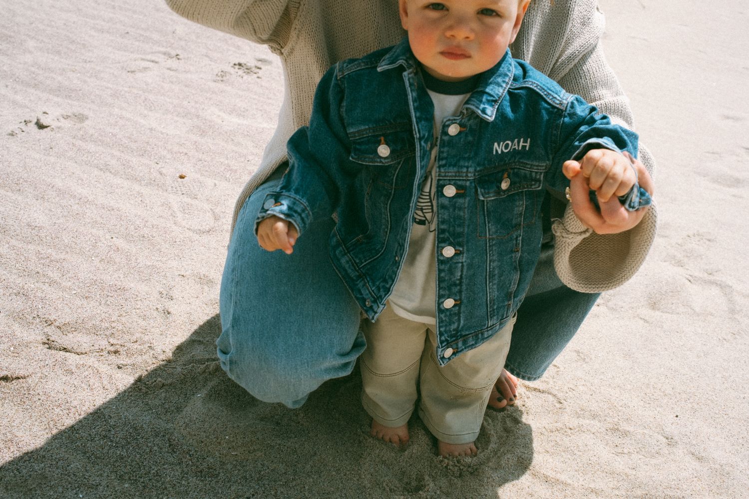 Close-up shots showing small feet and denim clothing details on sandy ground.