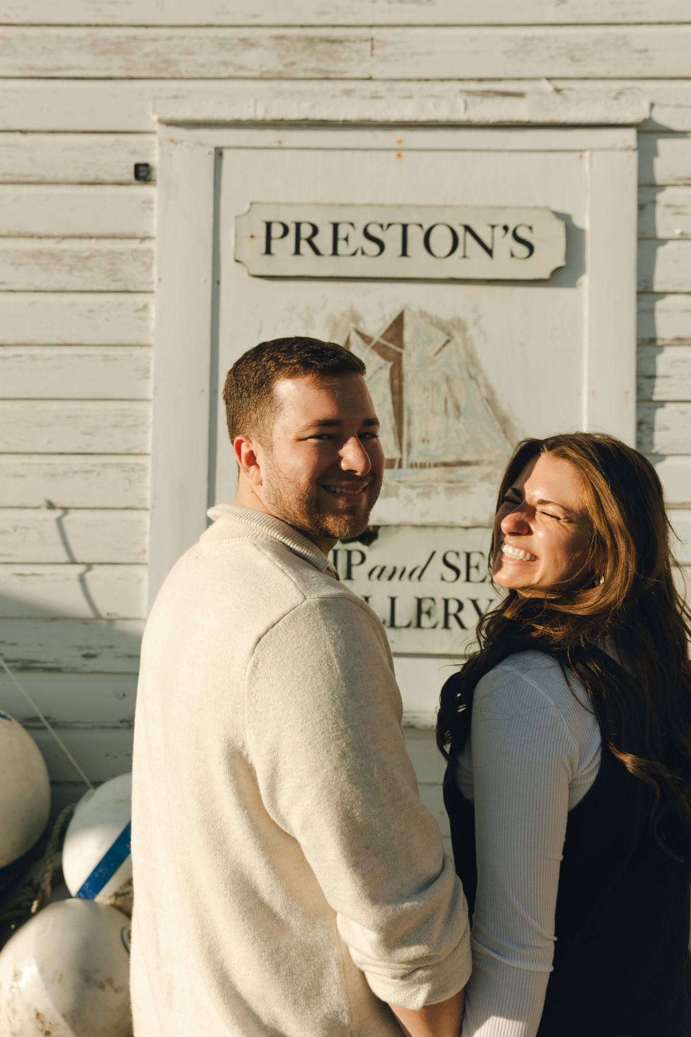 Couple smiling together in front of Preston's Ship and Sea Gallery sign on a sunny day.