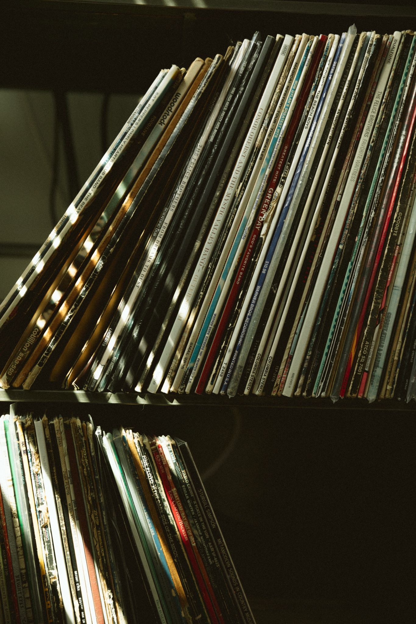 Collection of vinyl records arranged on shelves with dramatic lighting.