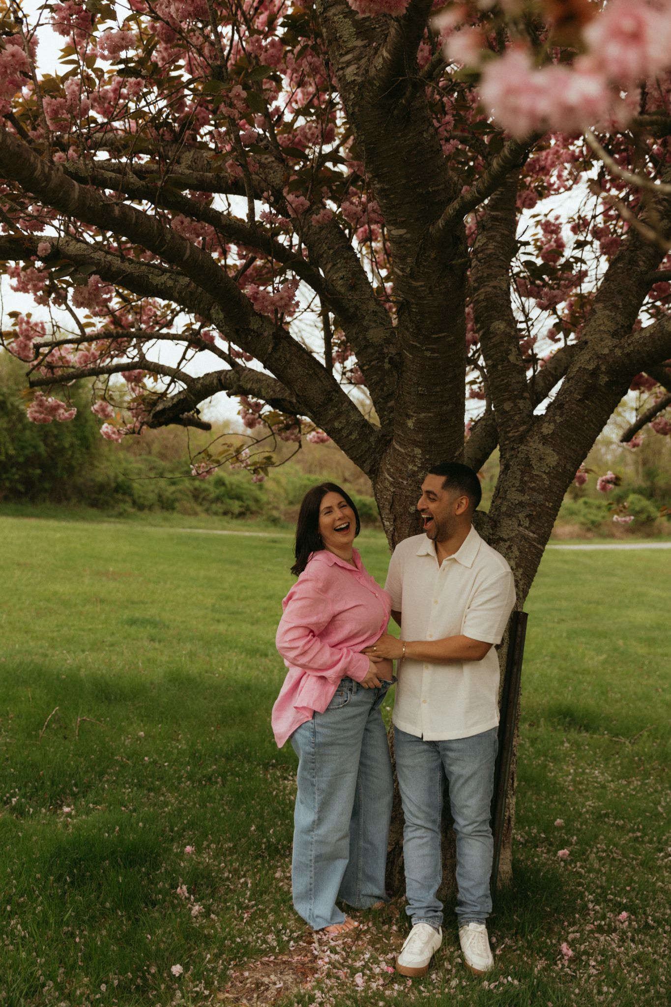 Couple sharing a tender moment under blooming cherry blossom trees in springtime.