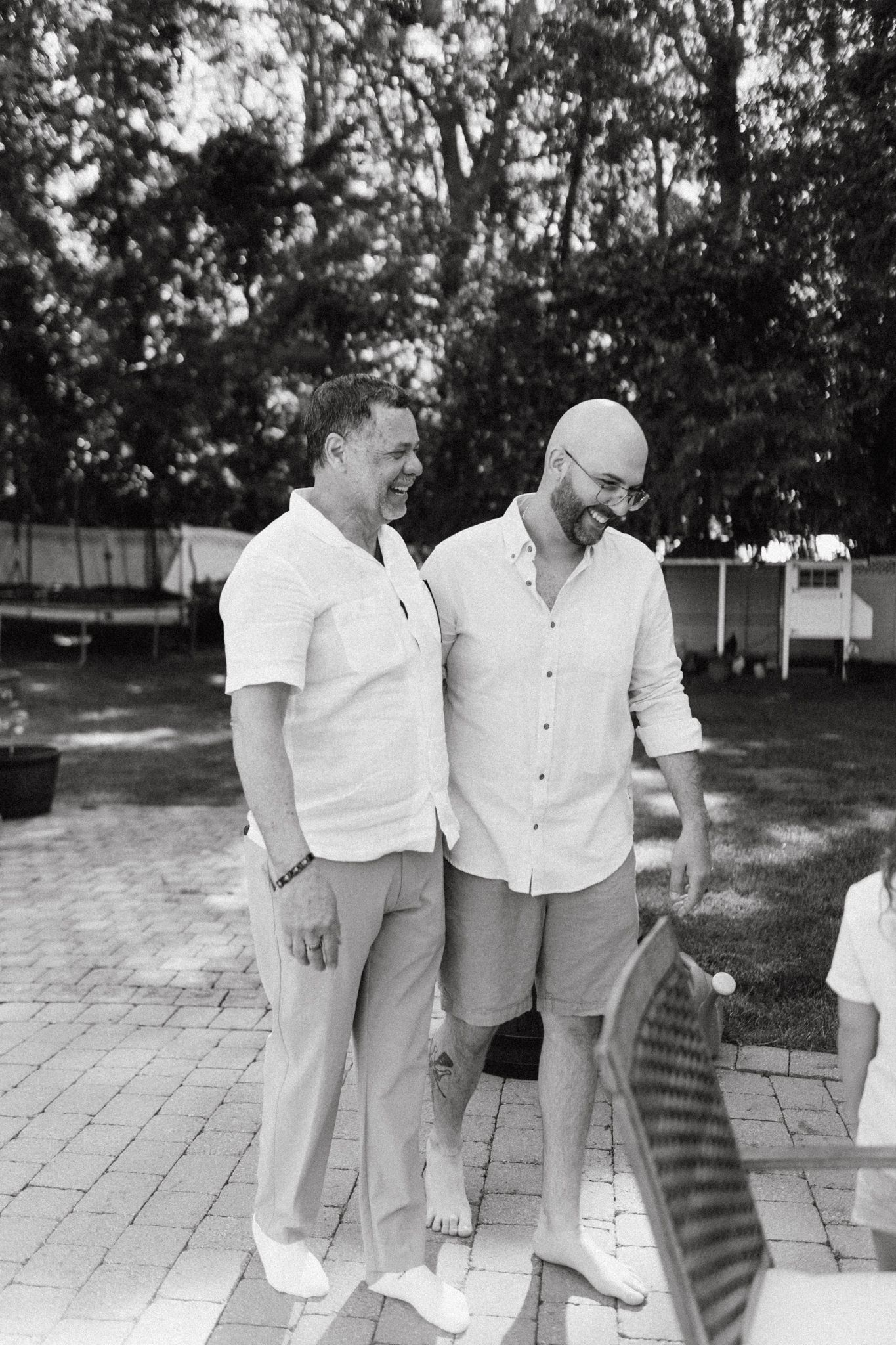 Black and white photo of people in white clothing standing on outdoor patio tiles.