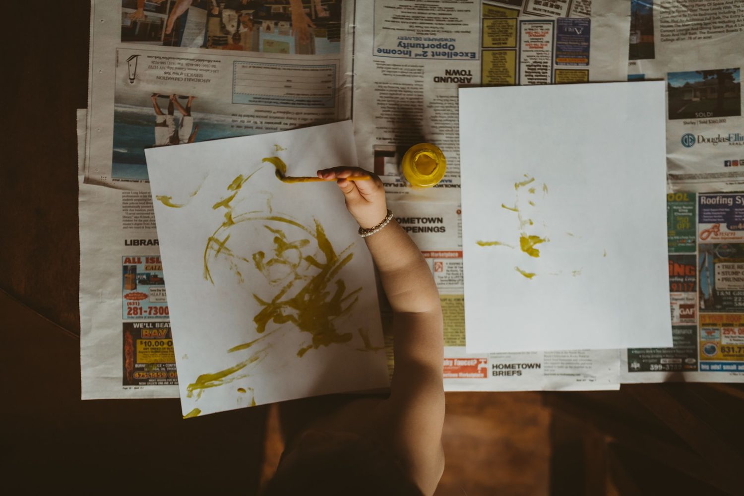 Hands working on artistic drawings spread across a table surface.