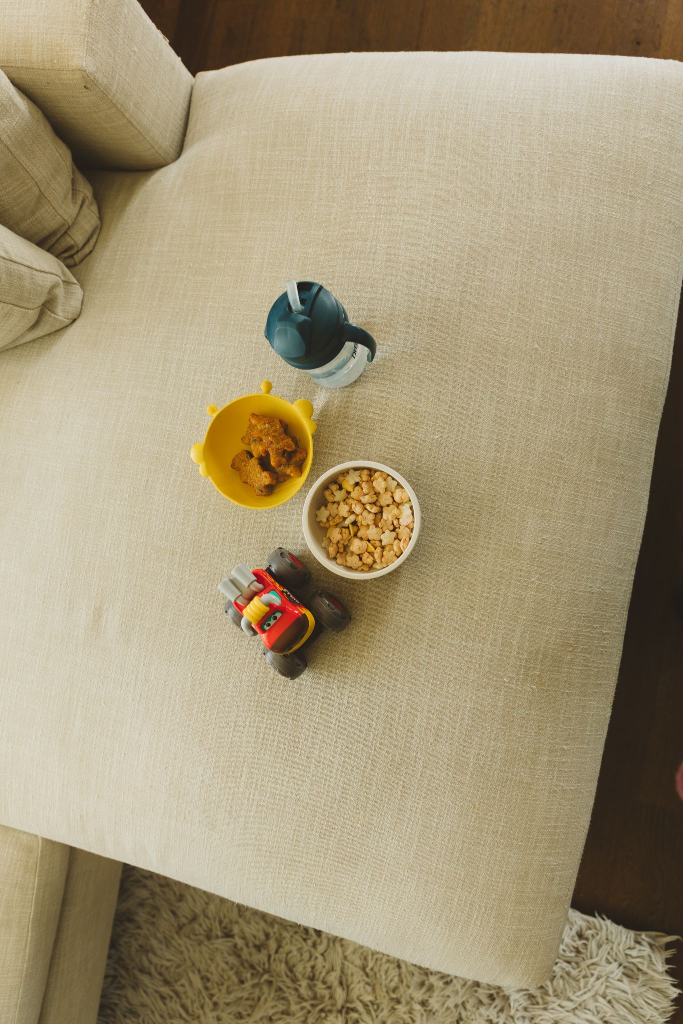 Overhead view of a small bowl of cereal and a blue cup on a light beige surface.