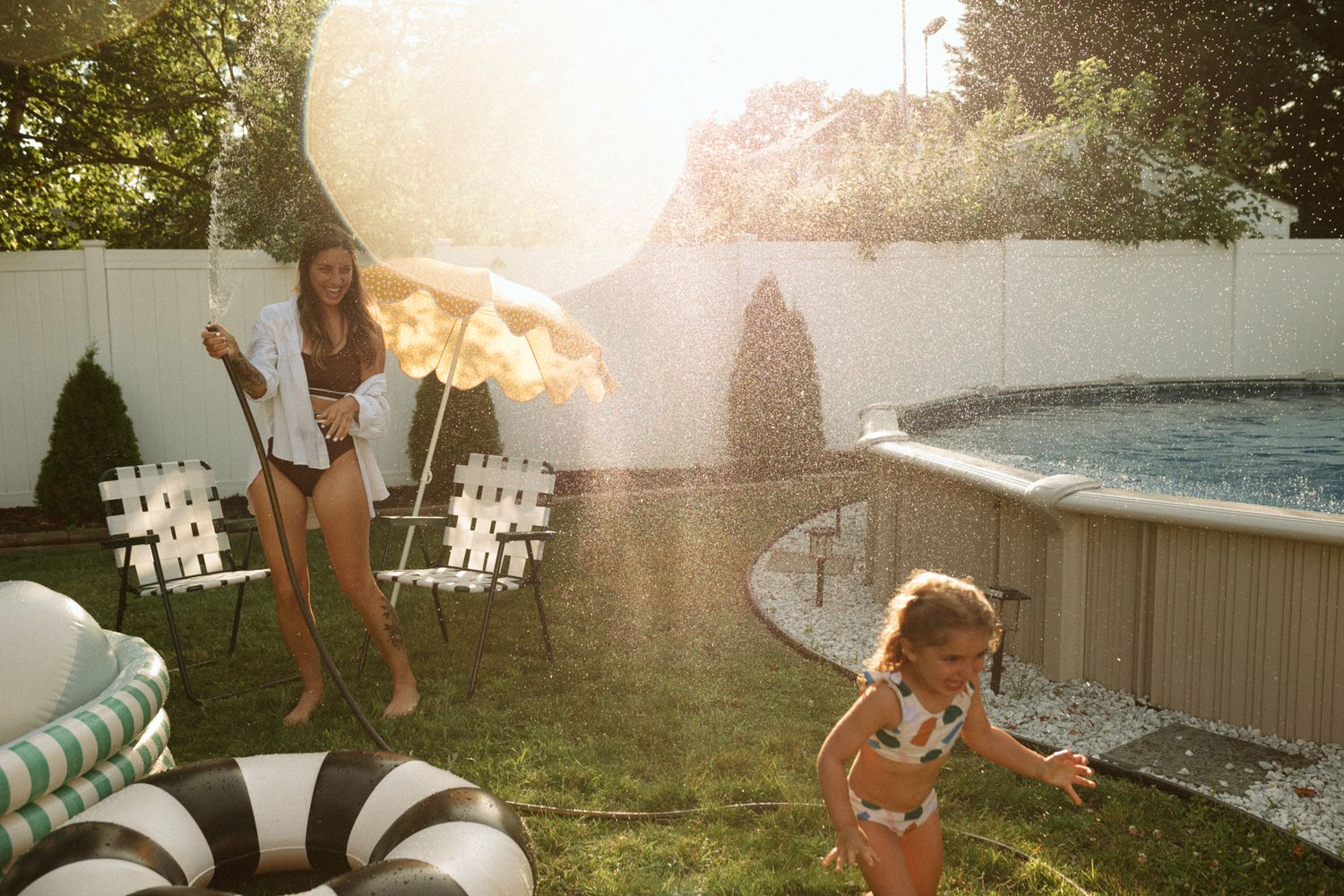 Summer backyard scene with pool floats and sun flare during golden hour.
