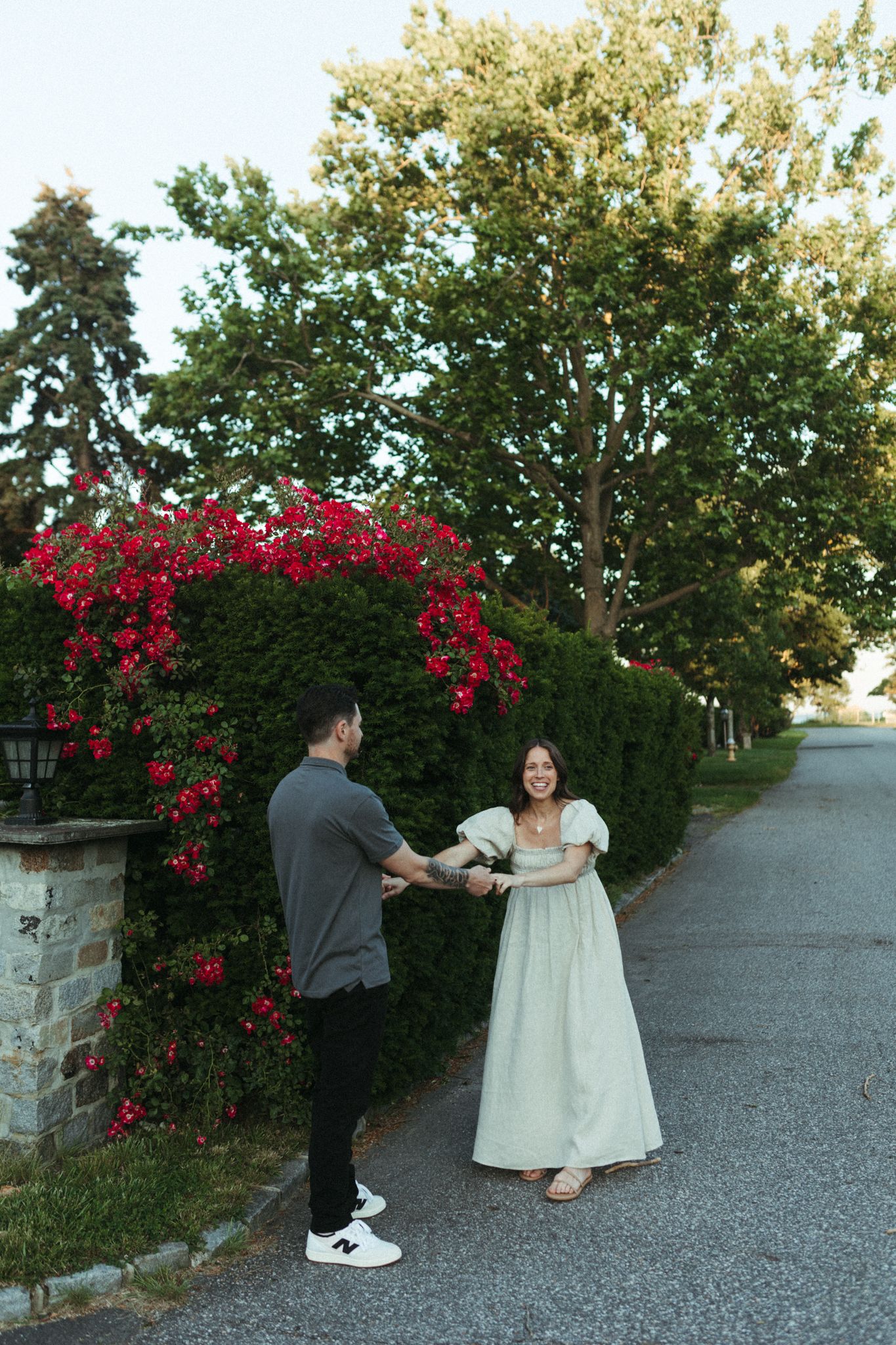 A couple dancing together on a path lined with blooming red roses.