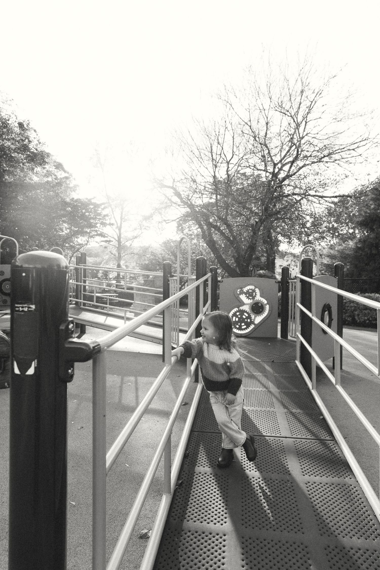 A black and white photo of someone playing on playground equipment.