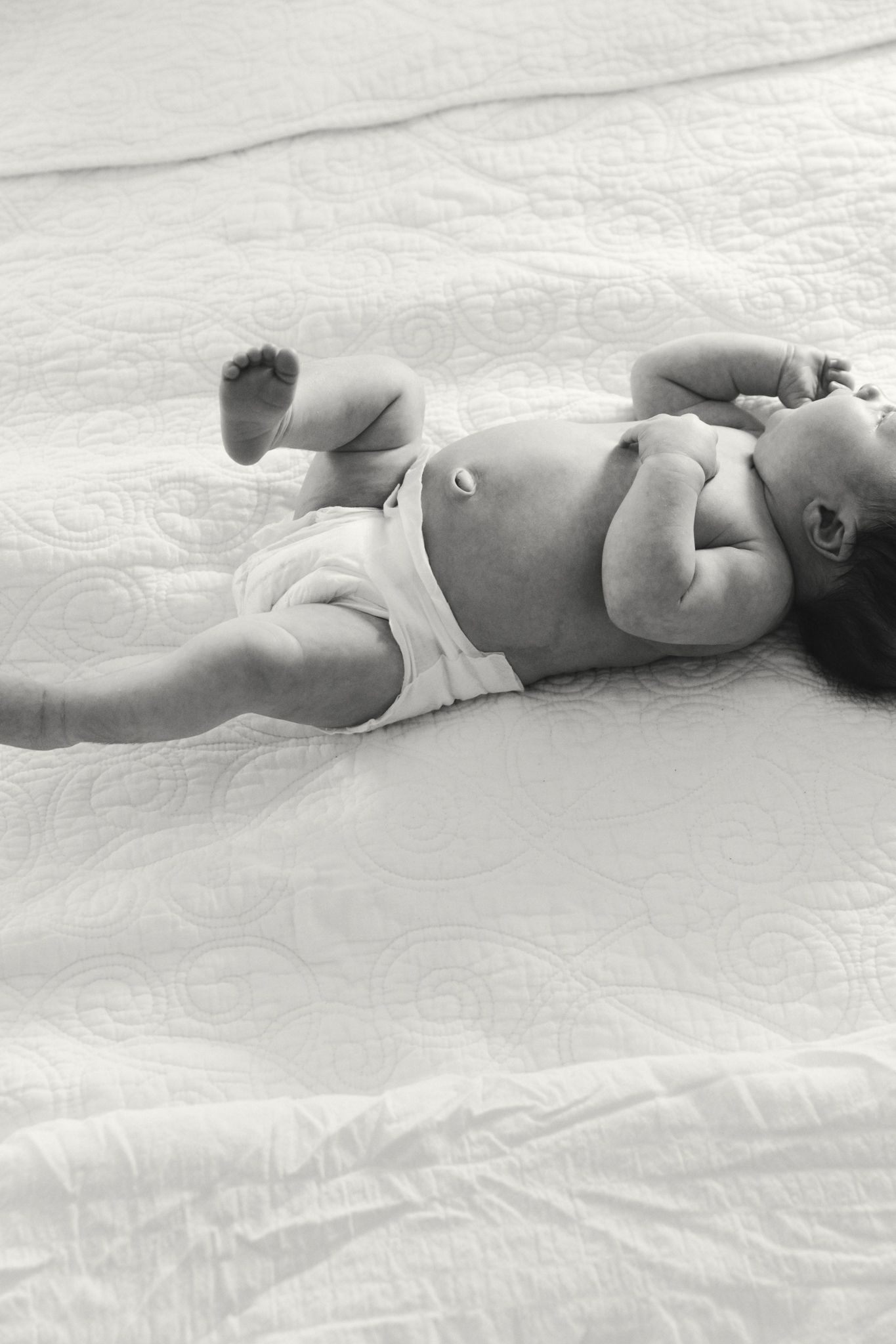 Black and white artistic photo series of a baby lying on textured fabric.