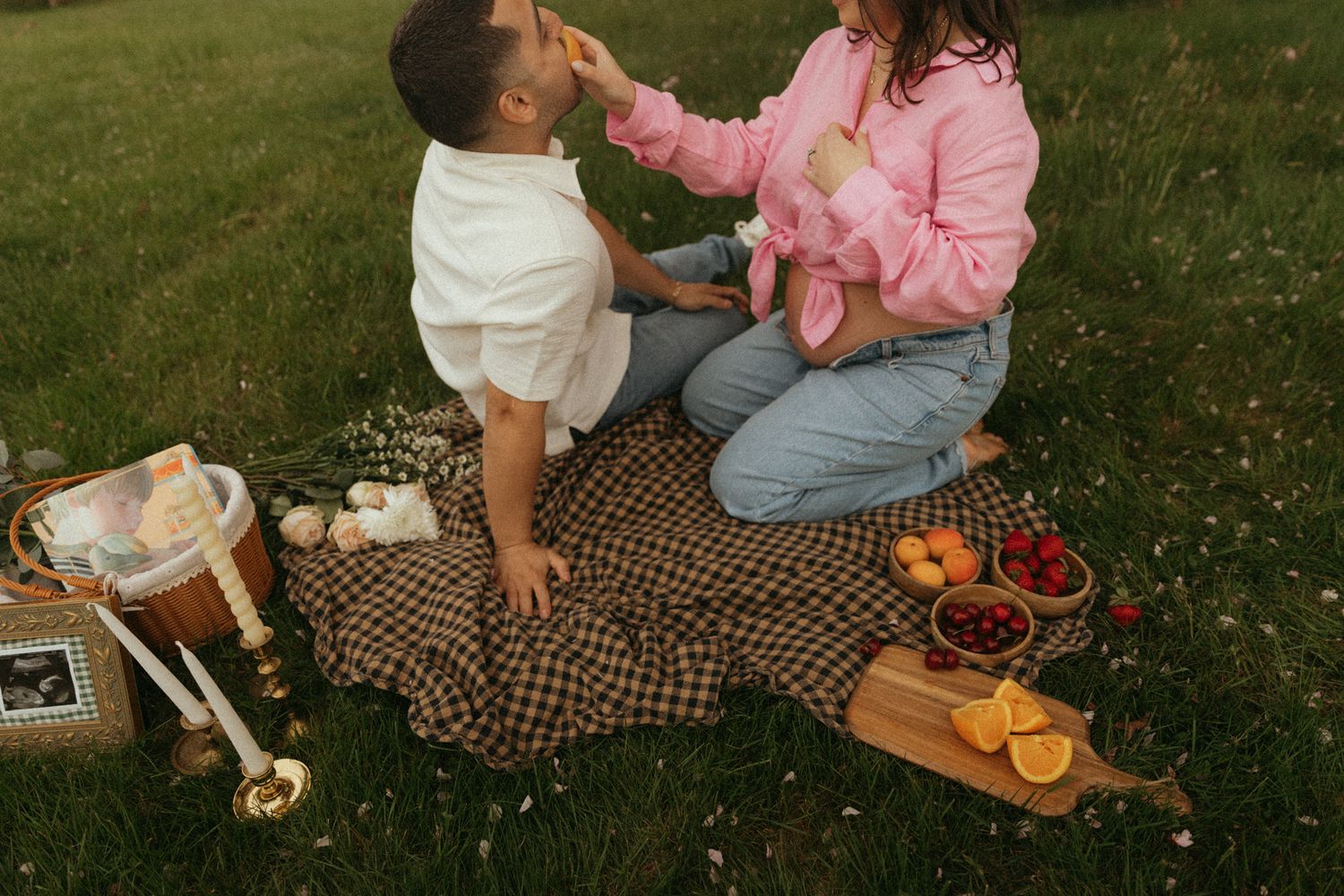 Romantic picnic setup with blanket and food under blooming cherry trees.