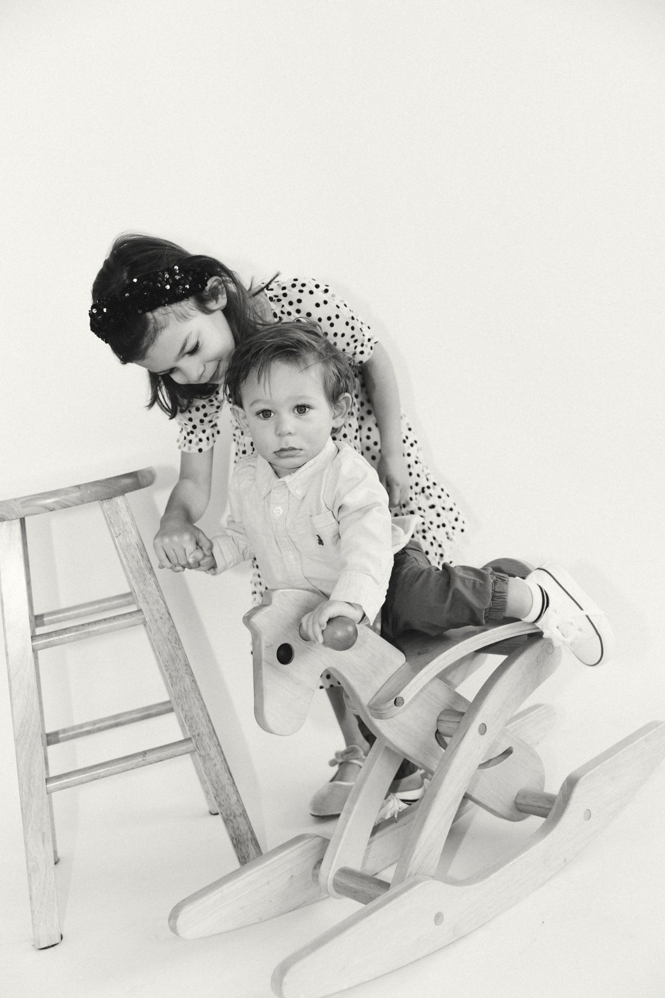 Playful sequence on a wooden ladder showing movement and joy in black and white.