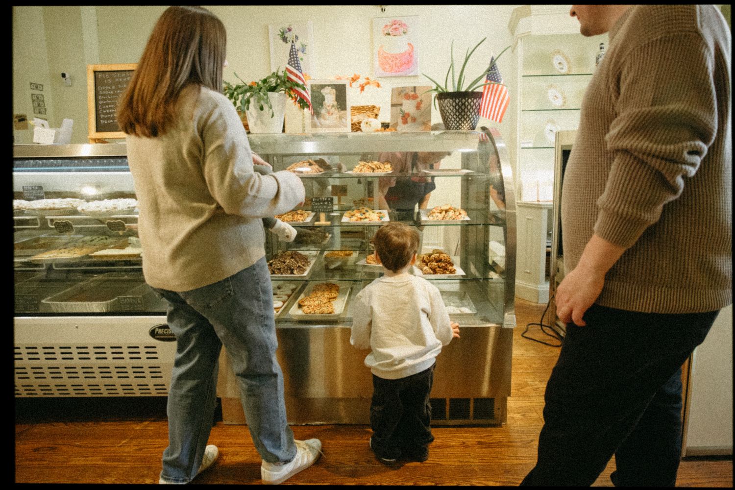 People browsing in a bakery with display cases and shelves of baked goods.