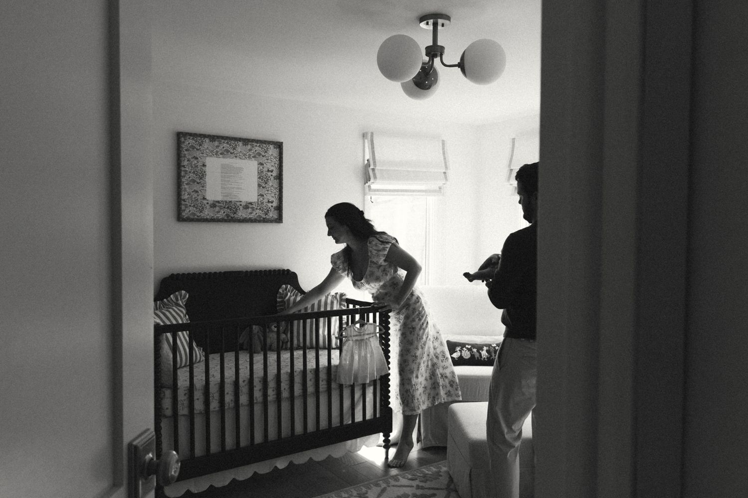 Silhouettes in a dimly lit nursery with crib and window light.