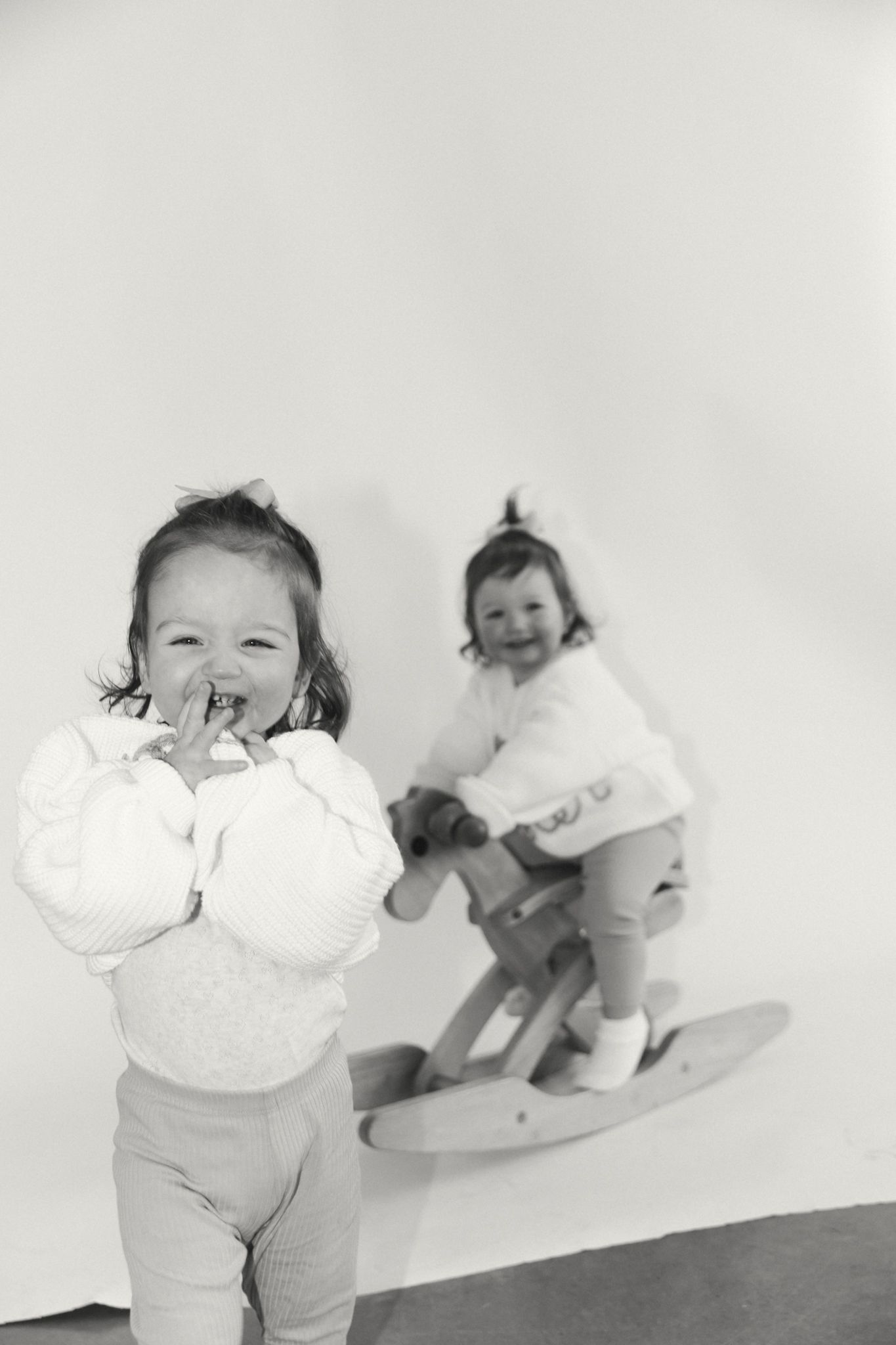 Progressive shots of a toddler in white clothing playing and smiling against a light backdrop.