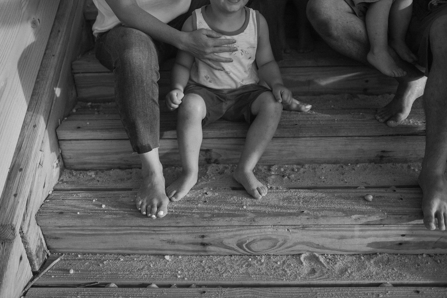 Wooden deck planks with bare feet visible in black and white.