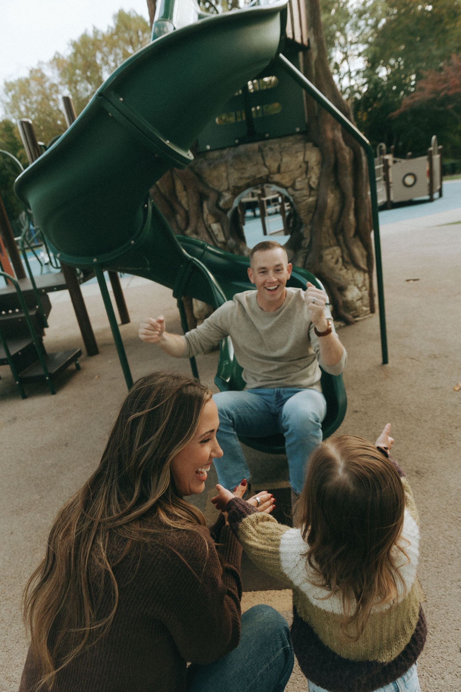 A joyful scene at a playground with people enjoying themselves near play equipment.