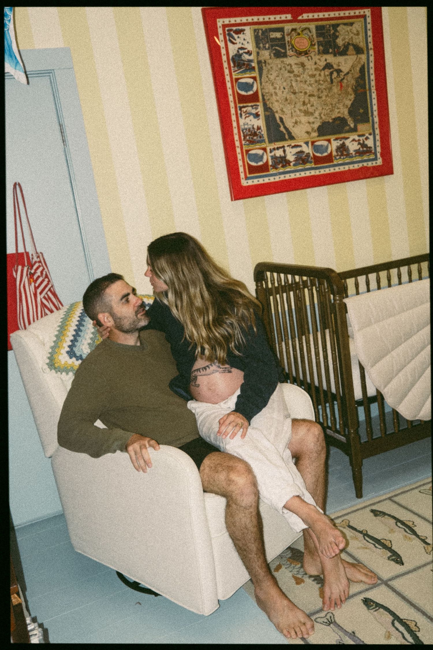 Two people relaxing together on a couch in a room with striped wallpaper.