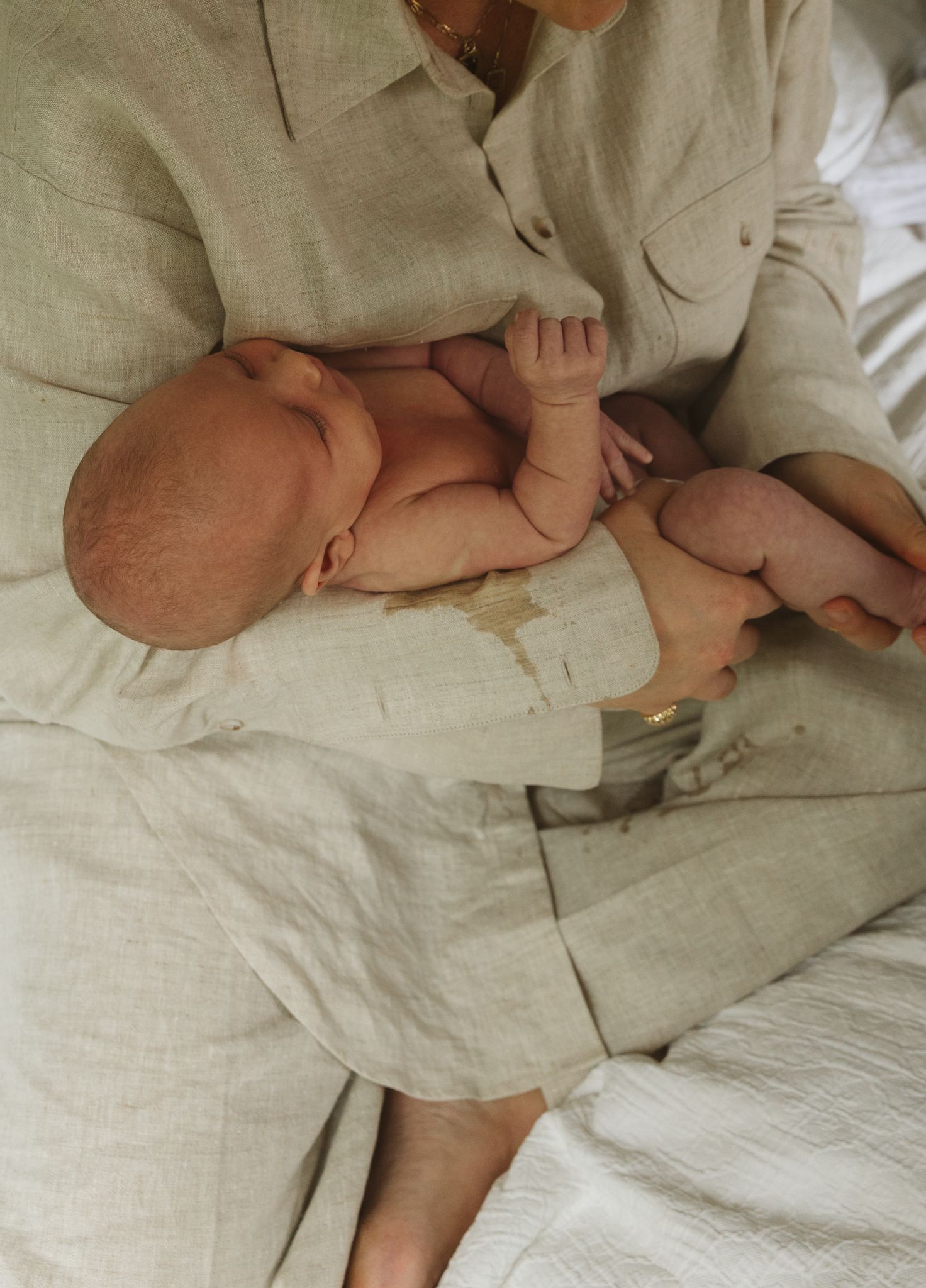 Close-up of baby feet and hands on light linen bedding.