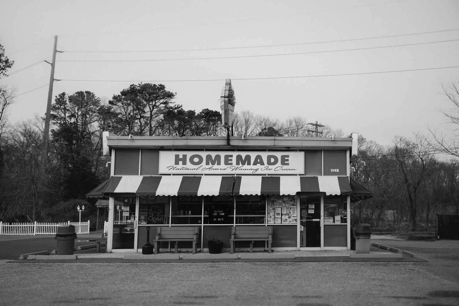 Black and white panorama of small town storefronts with a homemade sign visible in the distance.