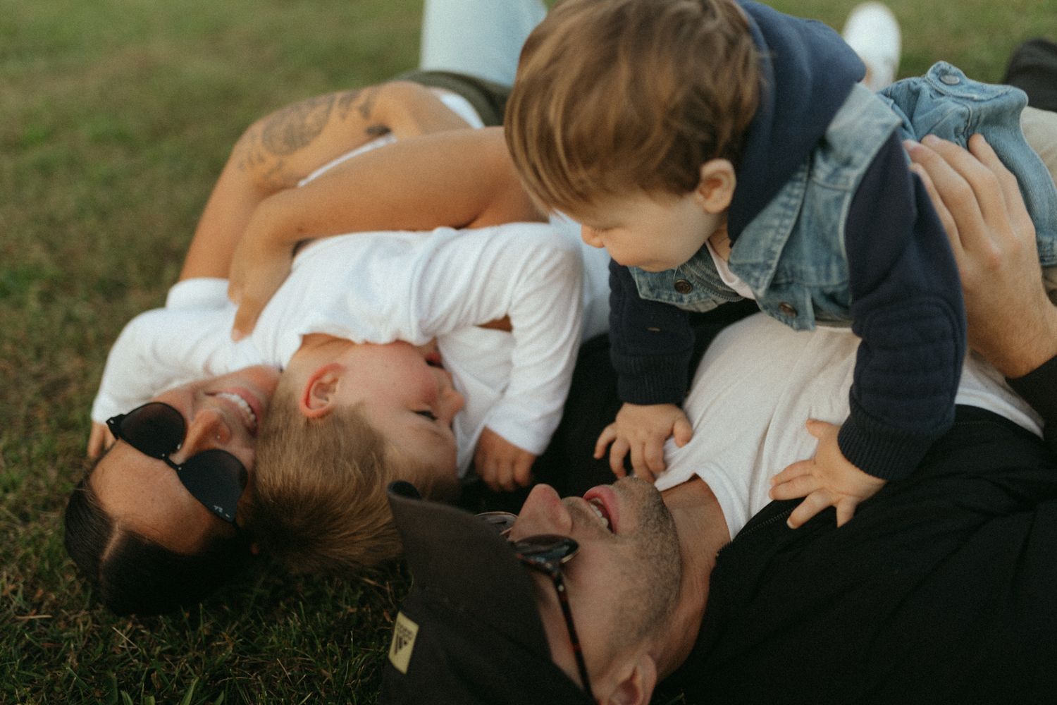 Group lying together on grass in a candid moment of joy and laughter.