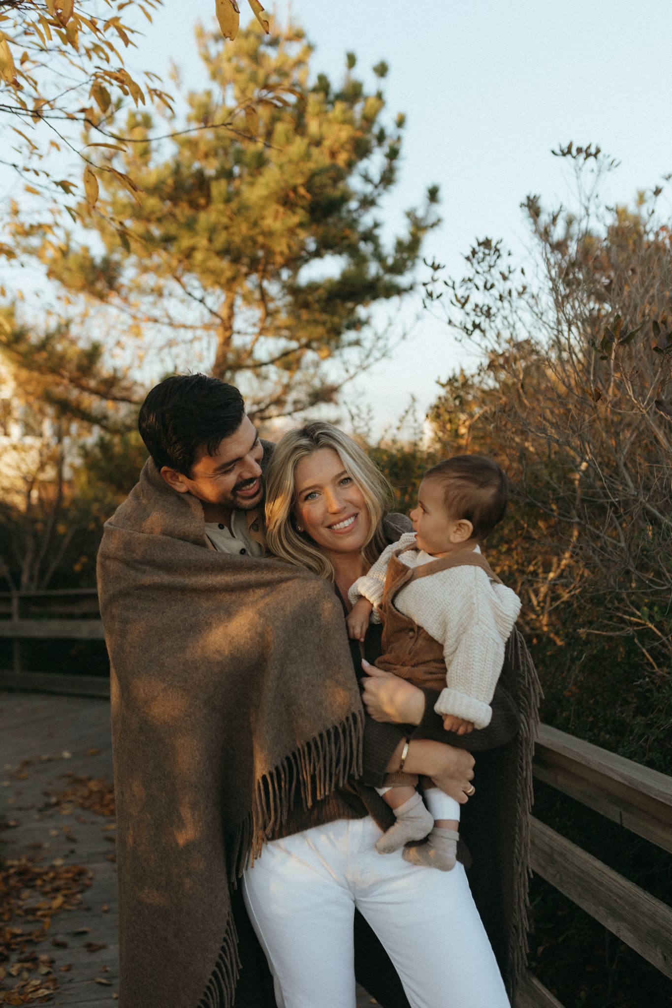 Joyful family moments captured on a wooden walkway surrounded by autumn trees.