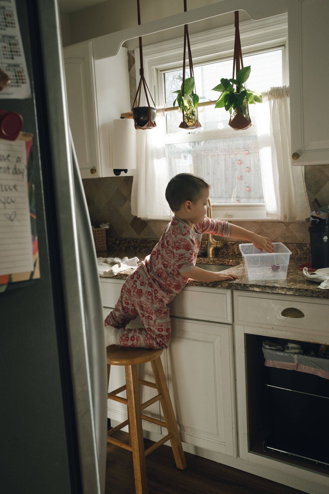 A sequence of photos showing someone climbing onto a kitchen counter to reach a window in a bright white kitchen.