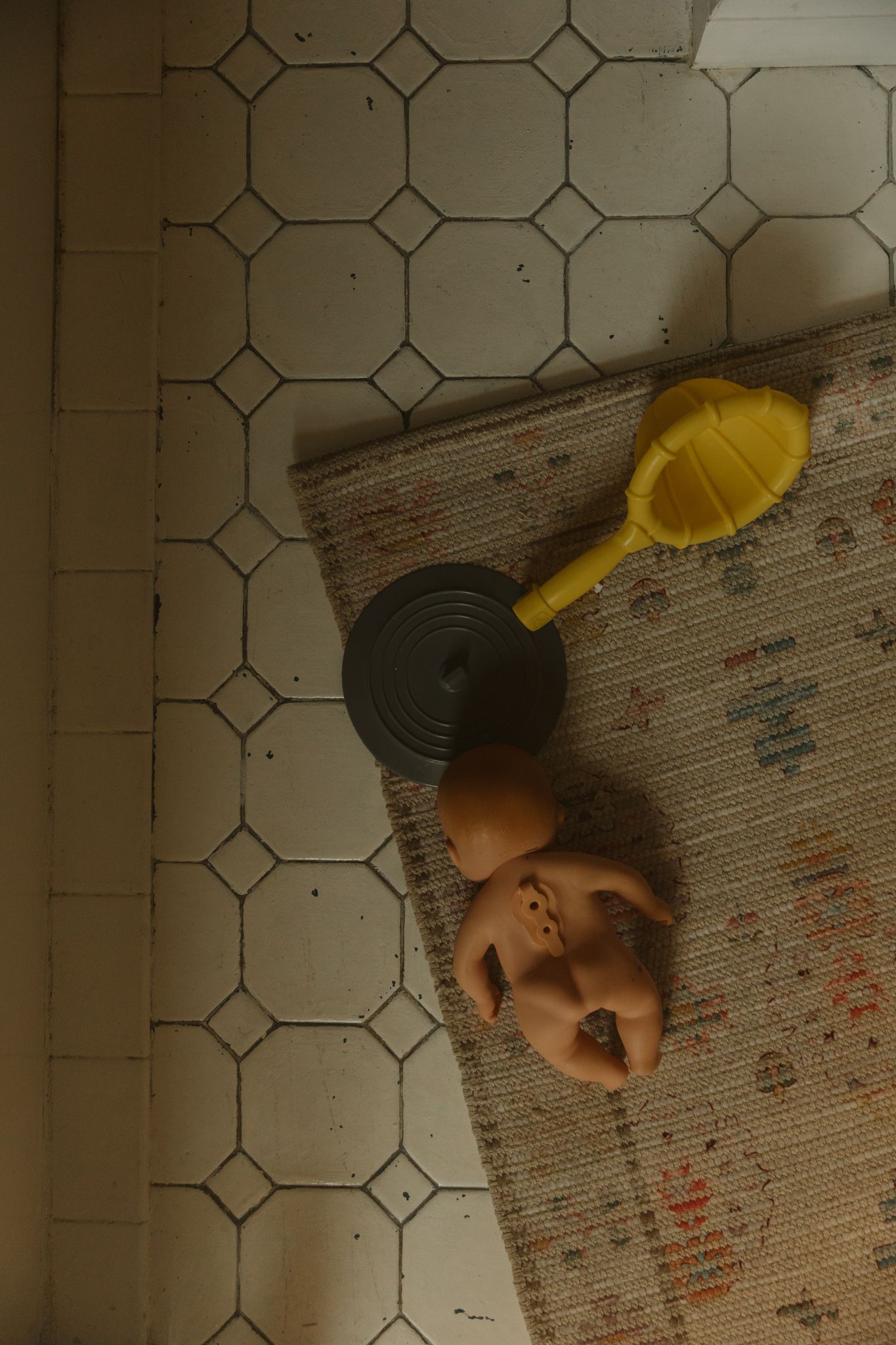 A yellow funnel and black record sit on a patterned tile floor beside someone resting.