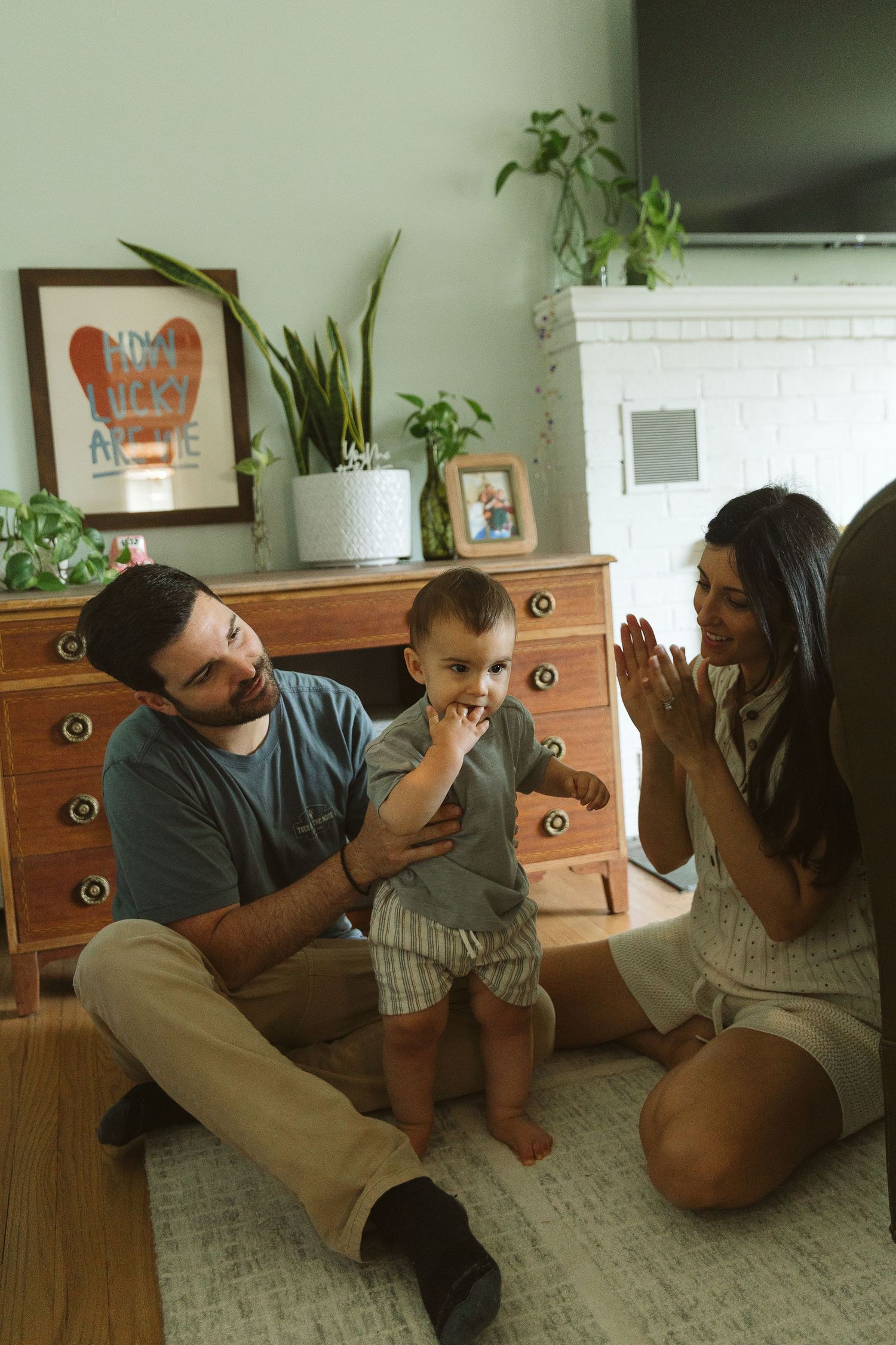 Family playing together on carpeted floor next to wooden dresser.
