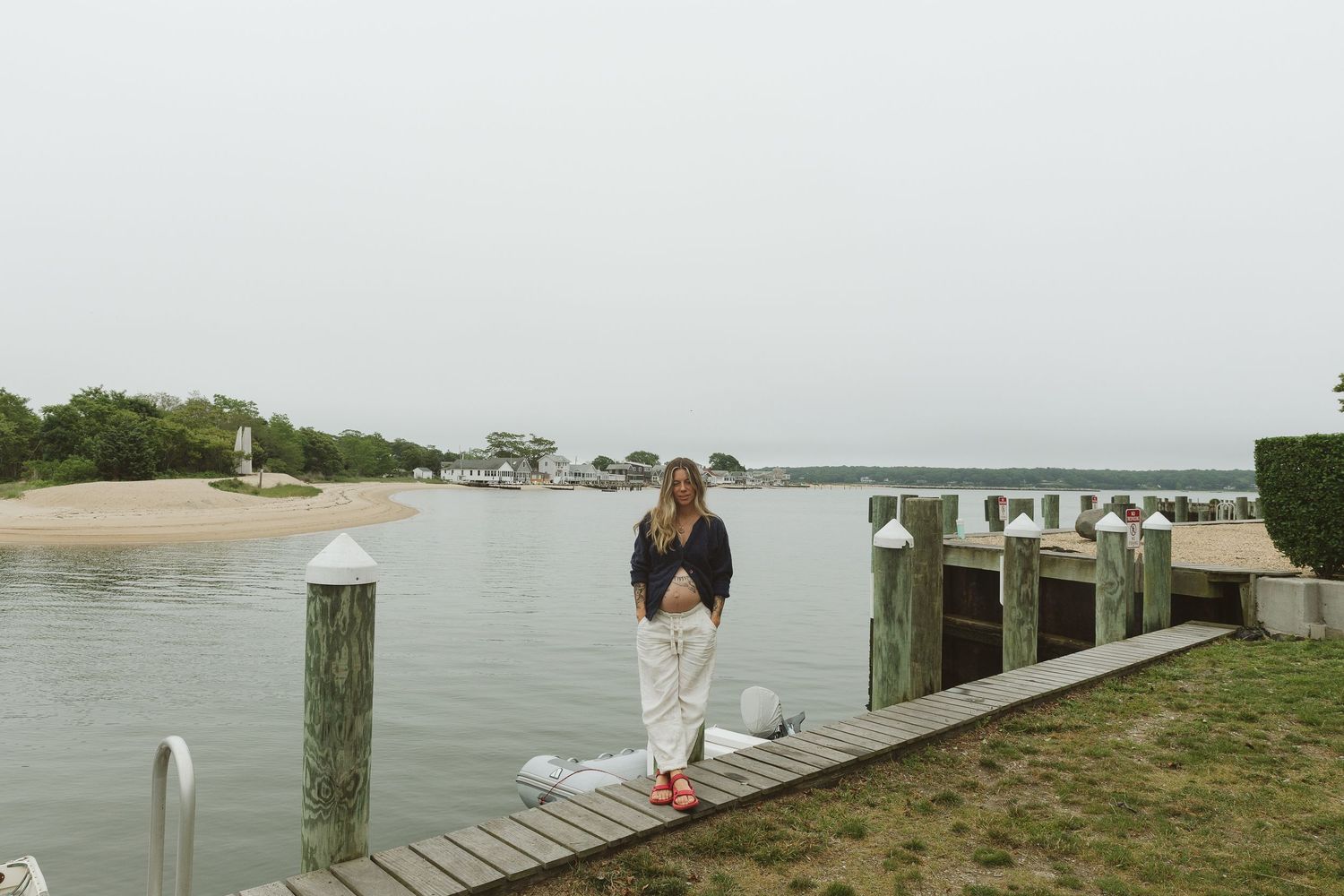 Overcast day on wooden dock with water and houses in background.