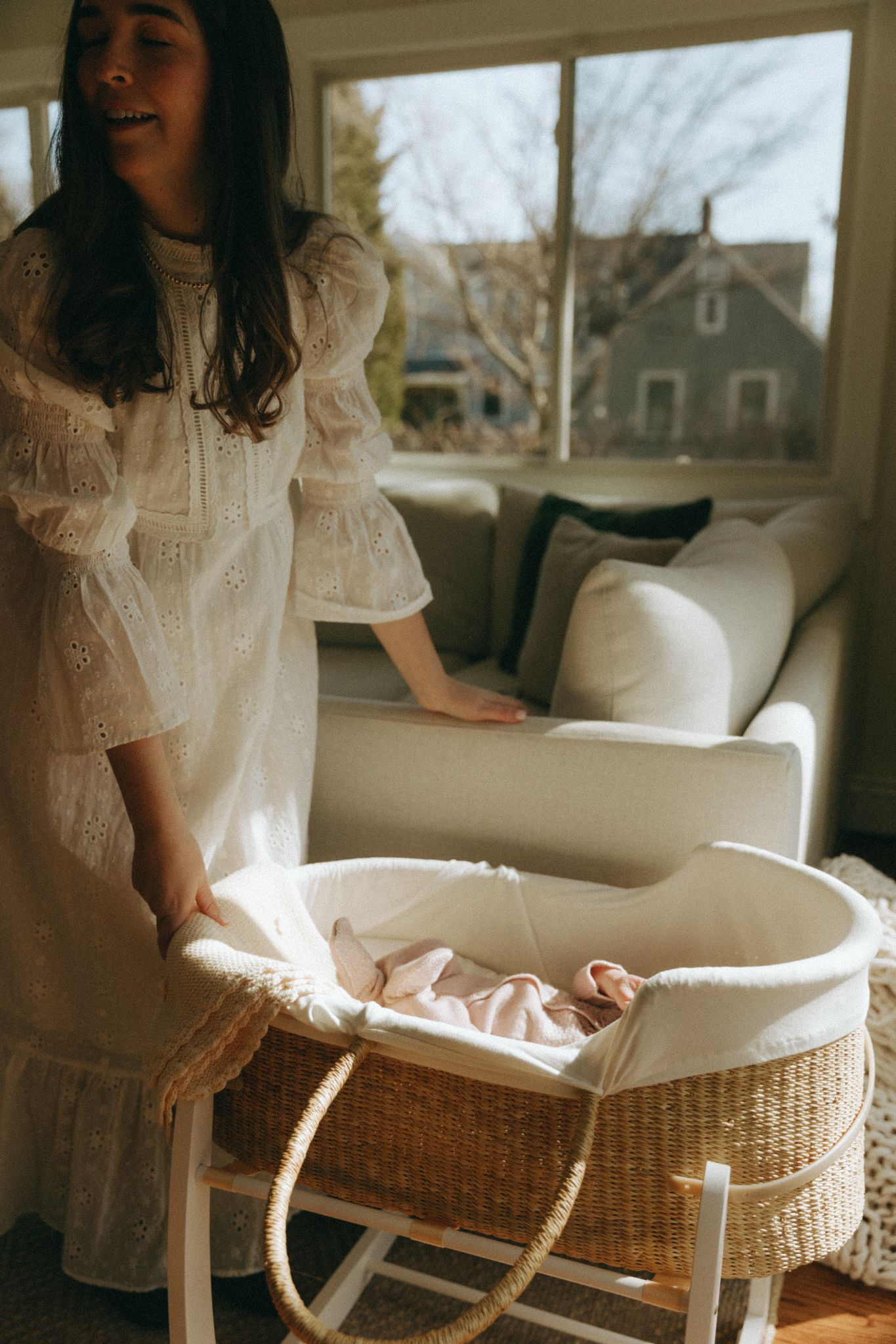 White wicker bassinet with delicate lining being prepared in sunlit room.