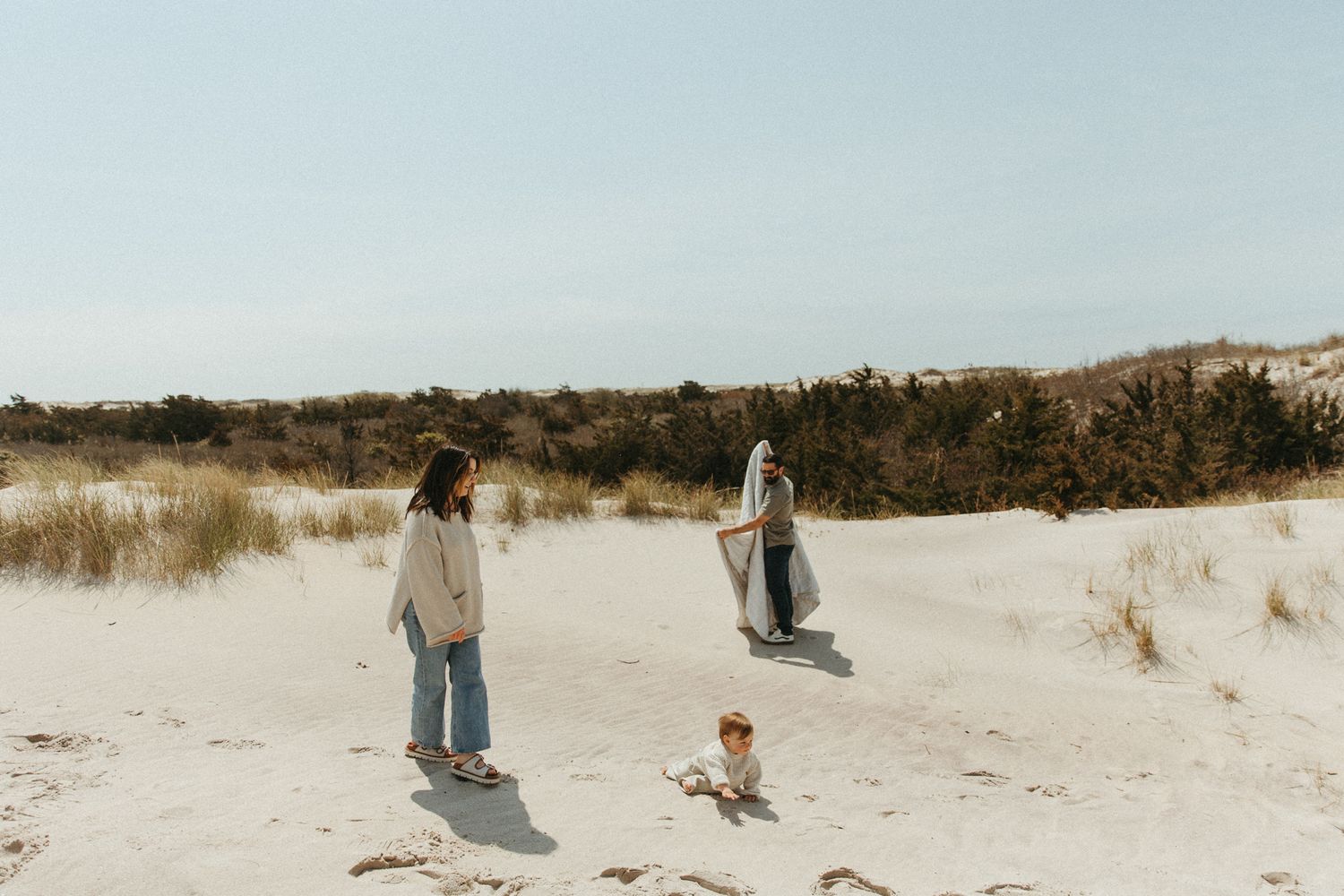 Wide landscape shots of sand dunes with people enjoying a sunny day at the beach.