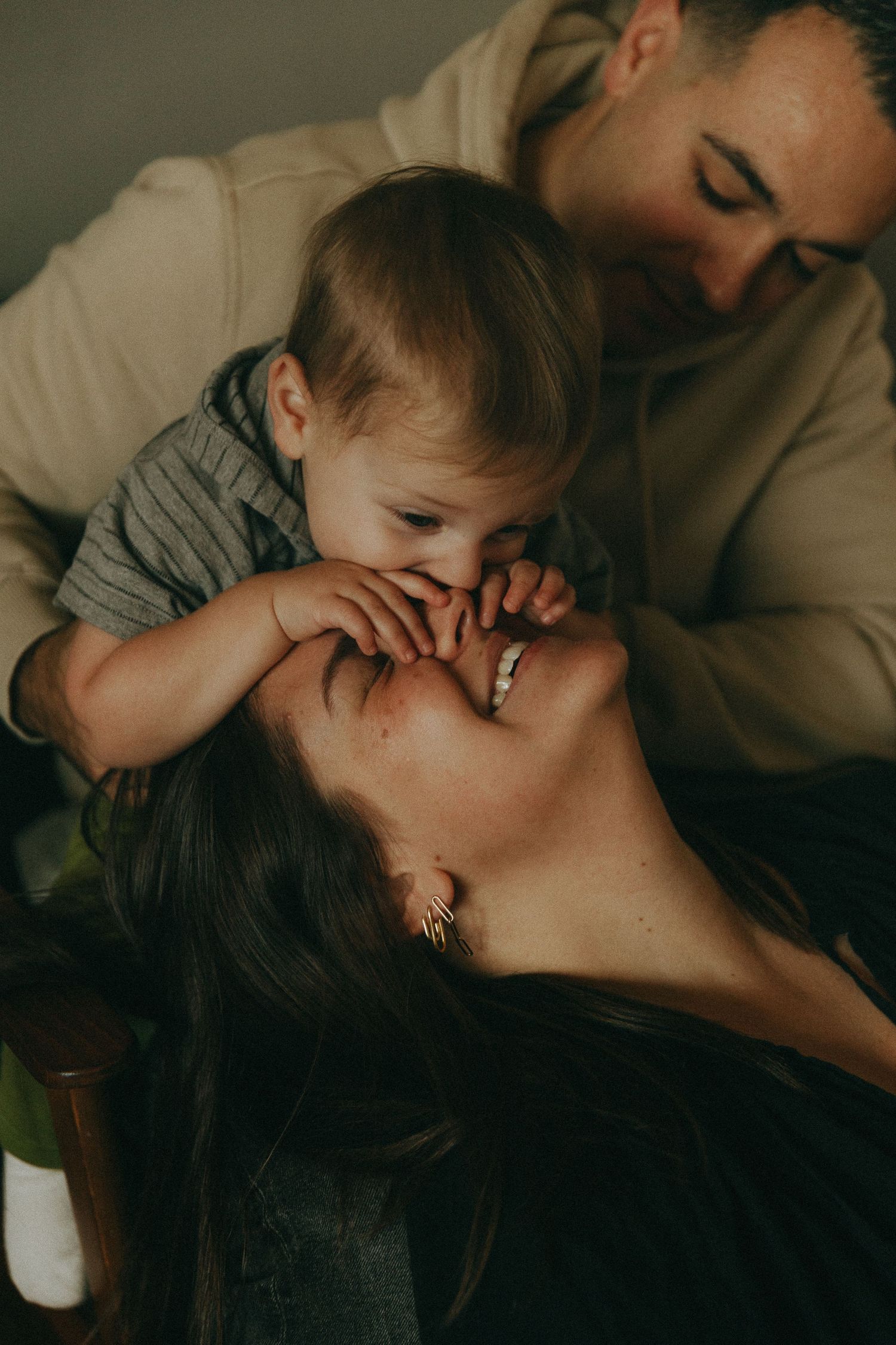 Parents lovingly gazing at baby who touches mothers face in warm intimate family moment.