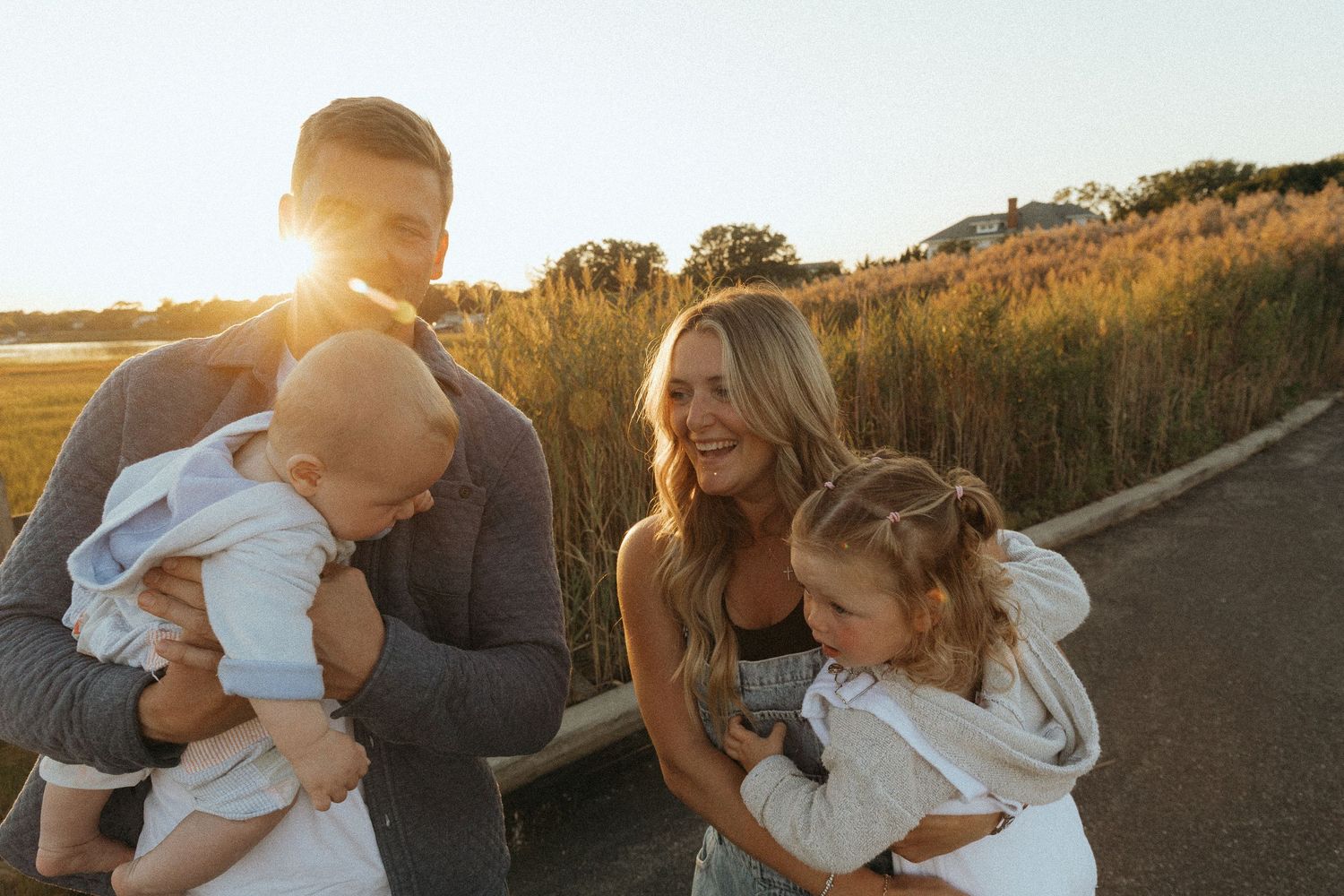 Happy family with two young children enjoying a golden sunset outdoors on a sunny day.
