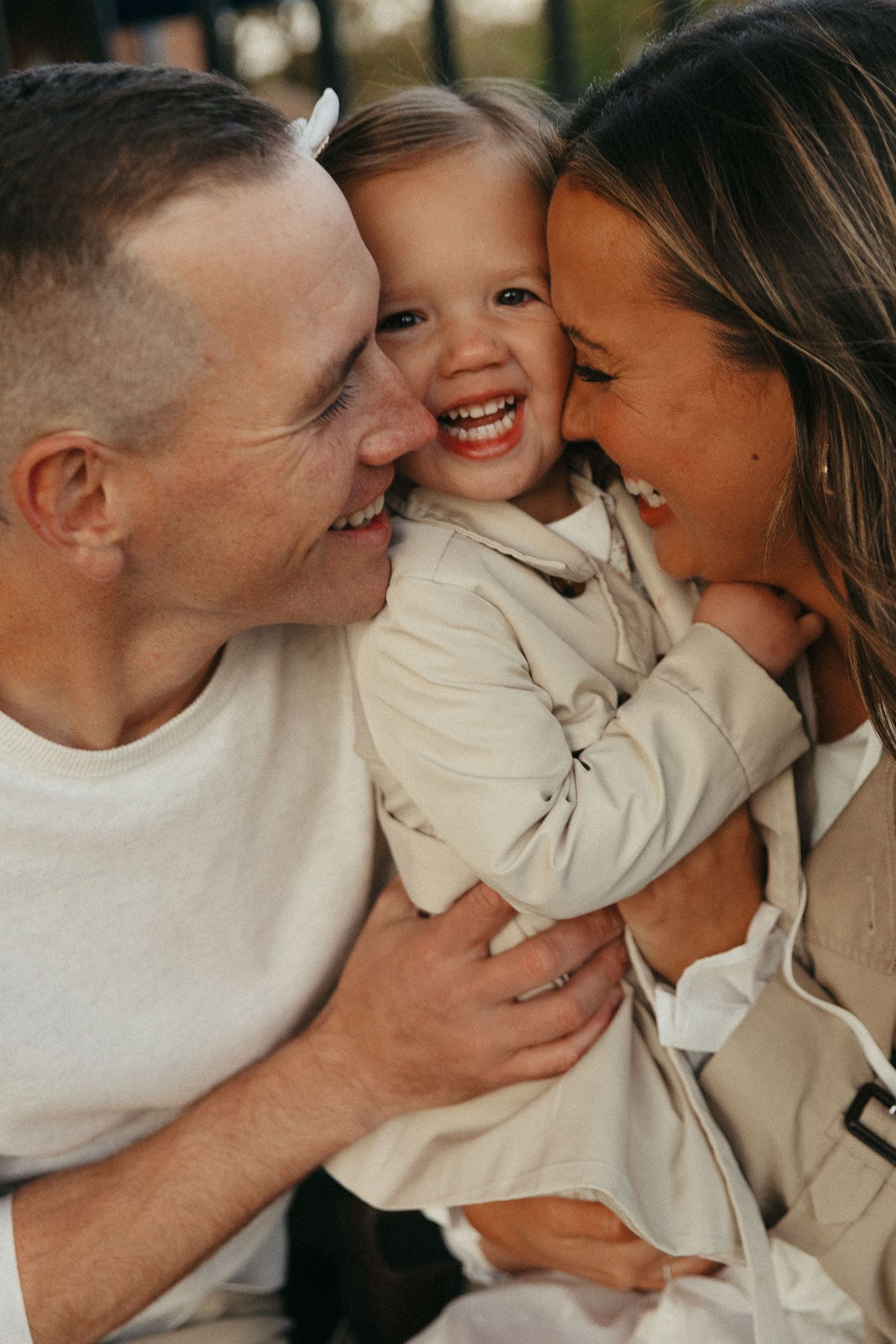 Intimate family moment captured in warm natural lighting wearing neutral colored clothing.