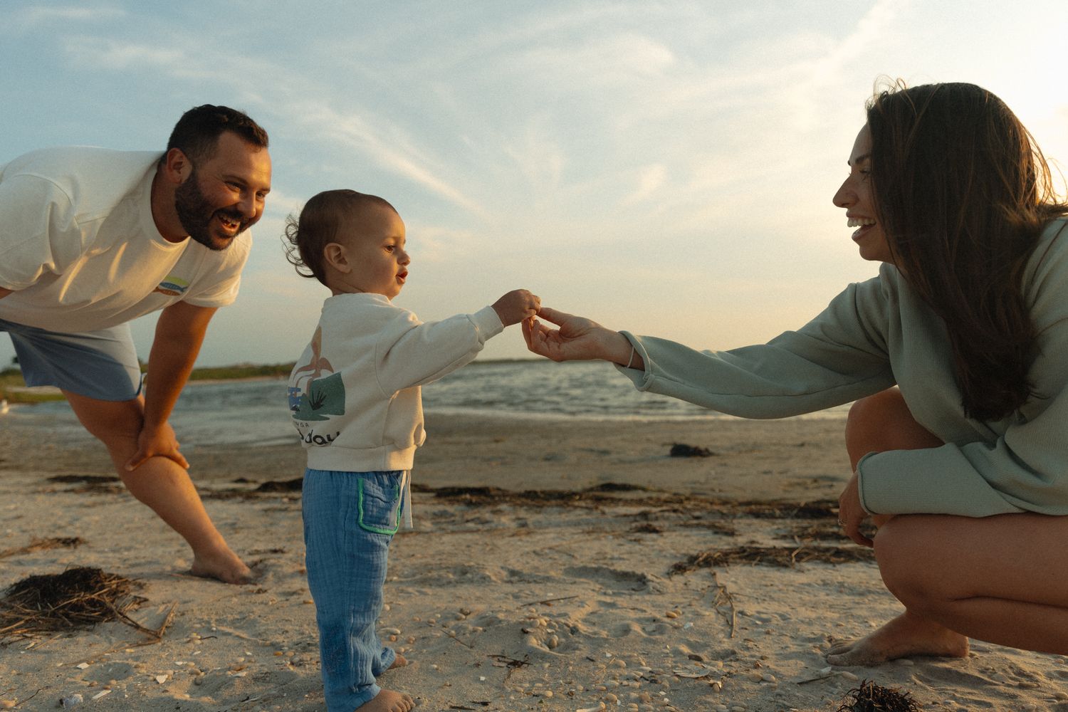 Family plays together on a rocky beach during golden hour.