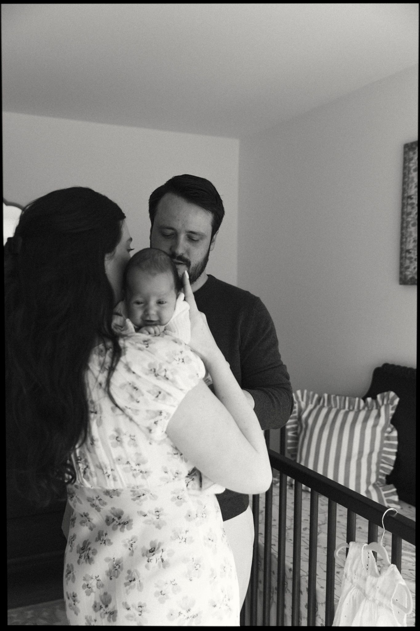 Tender moments captured in a nursery with dark furniture and natural lighting.