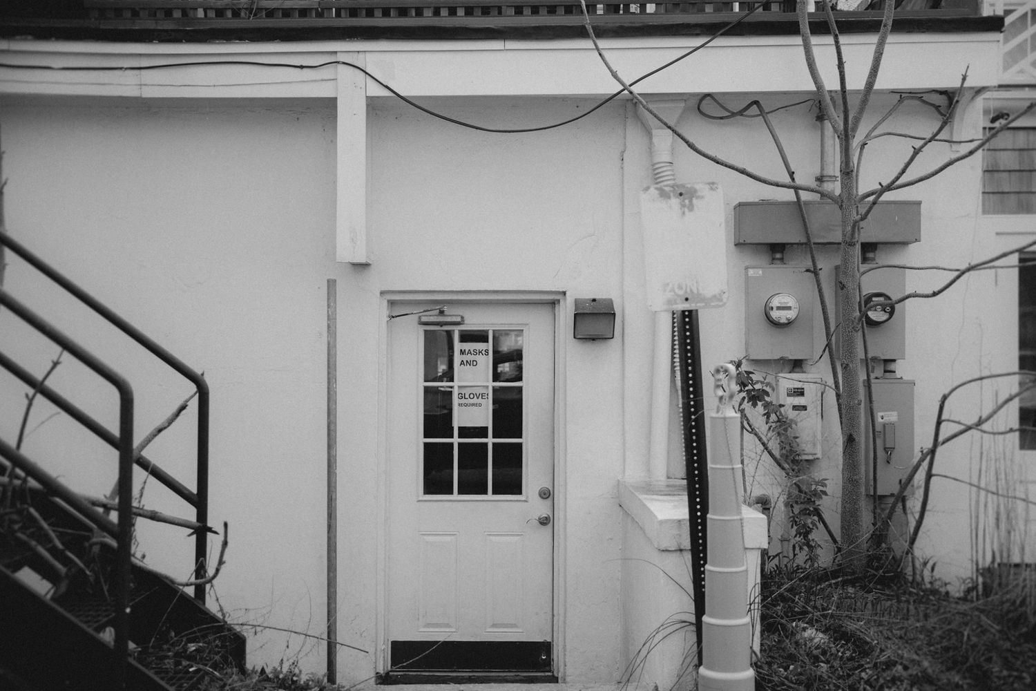 A white door with window panes on a building exterior with metal stairs.